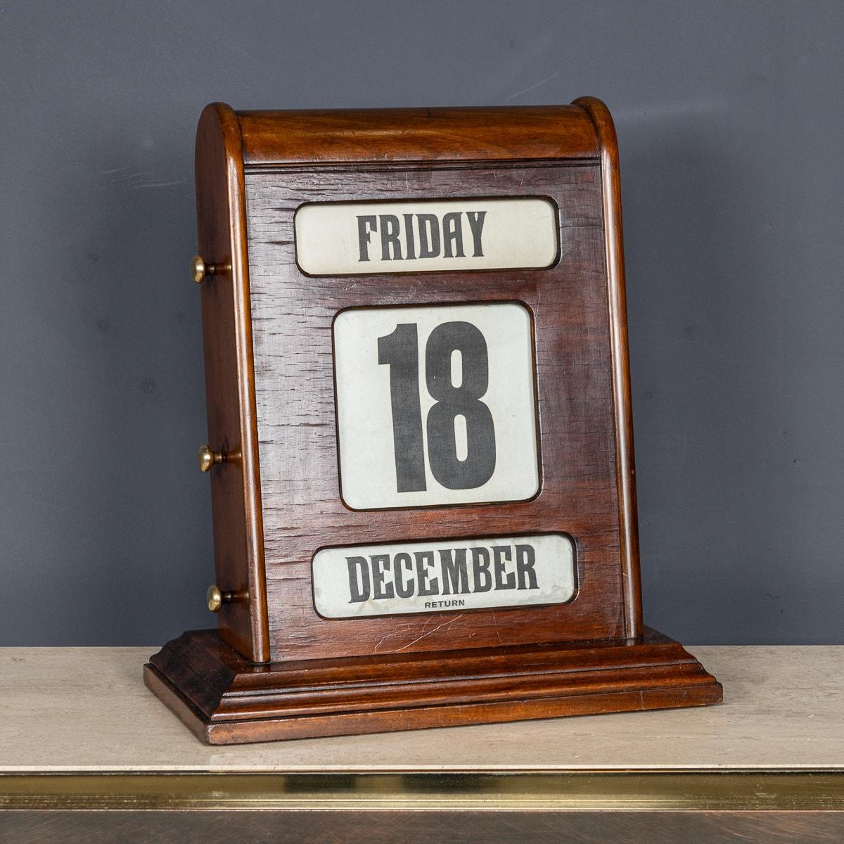 Vintage Tischkalender aus der Mitte des 20. Jahrhunderts, aus Mahagoni und Messing. Mit den drei Knöpfen auf jeder Seite lassen sich hinter drei verglasten Blenden der Tag, das Datum und der Monat vor- und zurückspulen. Ein echter Gesprächsstoff und