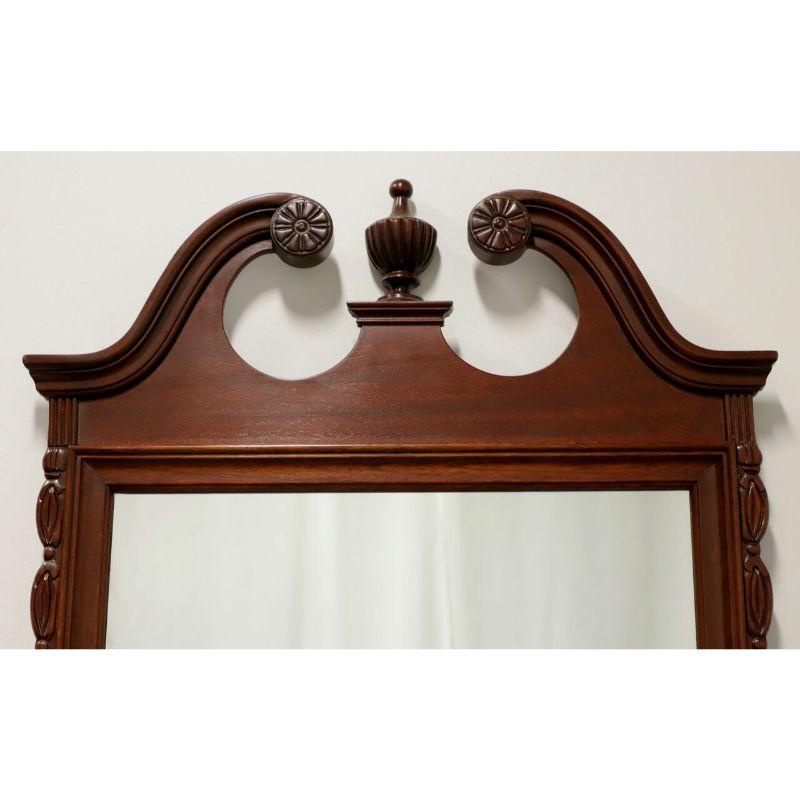 A Chippendale style wall mirror, unbranded, similar quality to Drexel Heritage or Henkel Harris. Mirror glass, mahogany frame with decorative carving to sides and bottom; pediment top with center finial. Made in the USA, in the late 20th