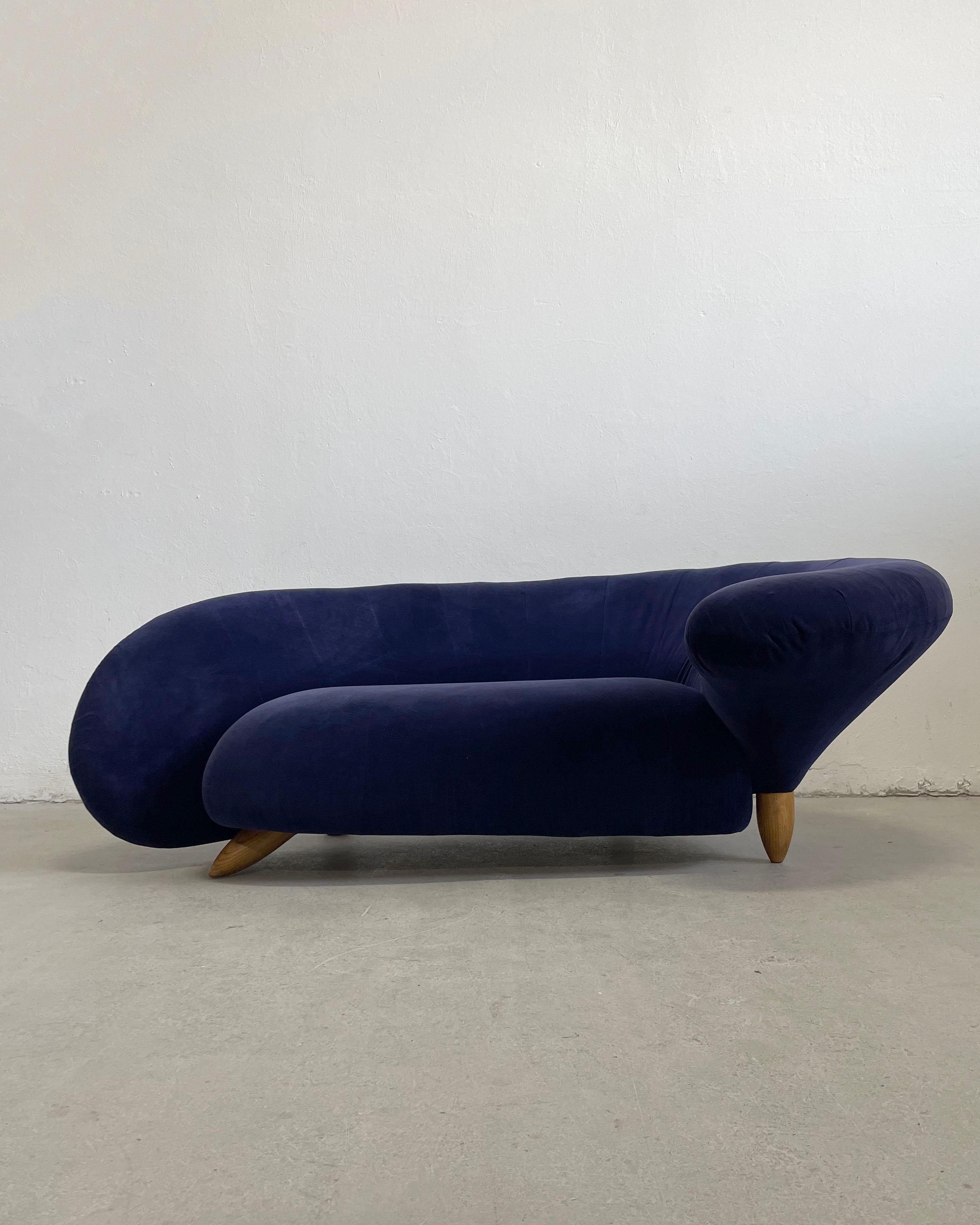 Exceptionally well crafted vintage curved sculptural sofa upholstered in original navy blue velvet.

The sofa features wooden legs and a wooden frame which is reinforced with a strong metal structure visible on the bottom side of the sofa. 
The