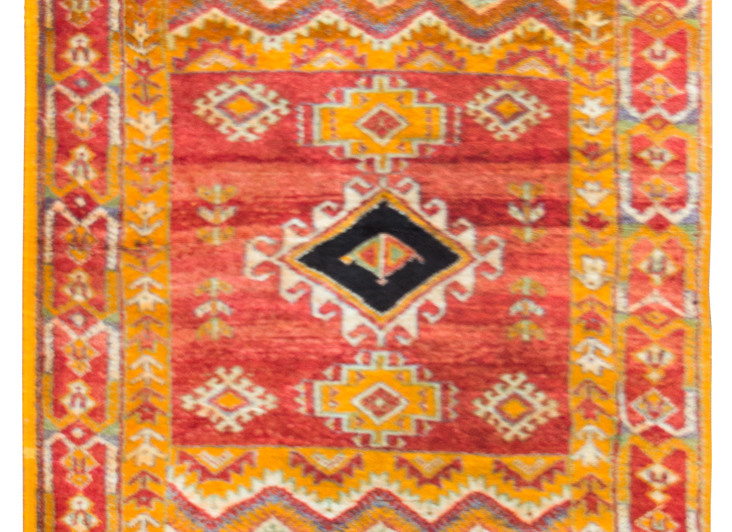 An incredible vintage mid-20th century Moroccan rug with a central stylized floral diamond amidst a square field of more stylized flowers, and flanked by a series of stripes with more diamonds, and all surrounded by a border of more repeated