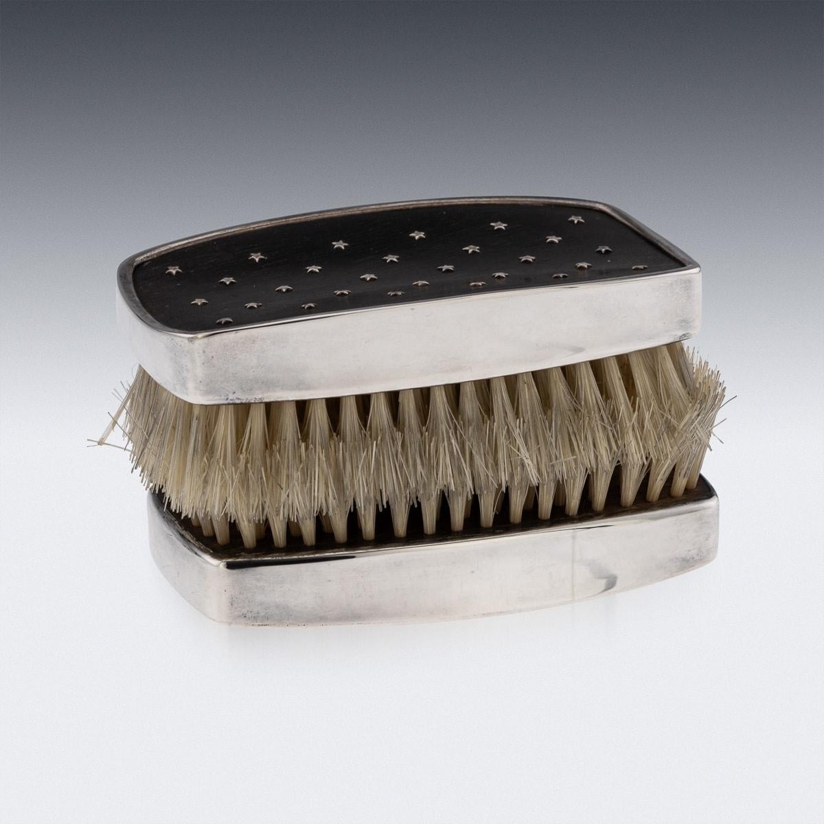 A pair of mid 20th Century English solid silver clothes brushes. The brushes feature a wooden handle which has a solid silver edge band. Throughout the top of the handle, there are small silver star shaped decorations imbedded into the wood finish.
