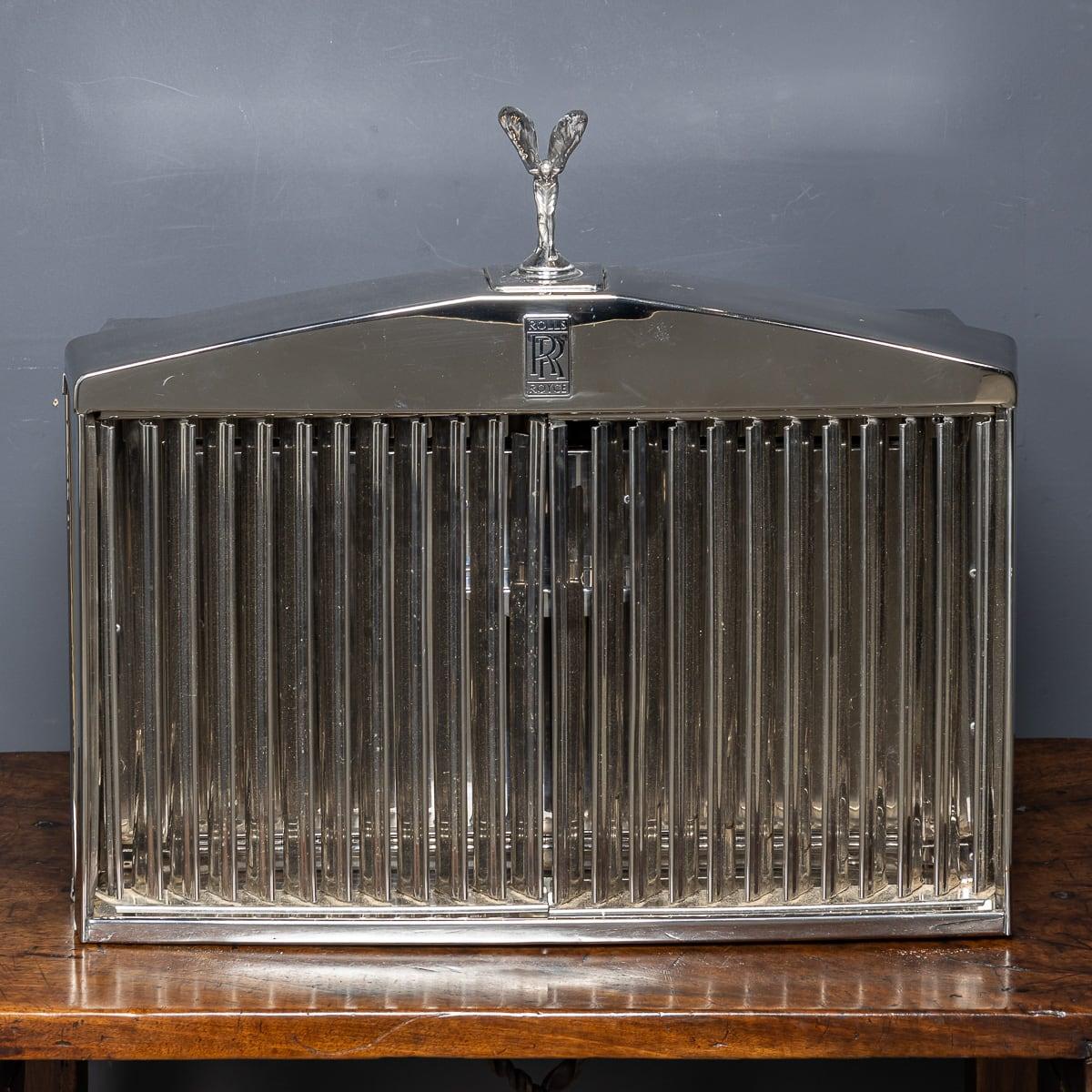 A 20th Century Rolls-Royce car grille with a retractable Spirit of Ecstasy ornament has been repurposed into a two-tier cigar humidor and accessories storage. Opening the vertical grille vents reveals three drawers featuring Louis Vuitton leather