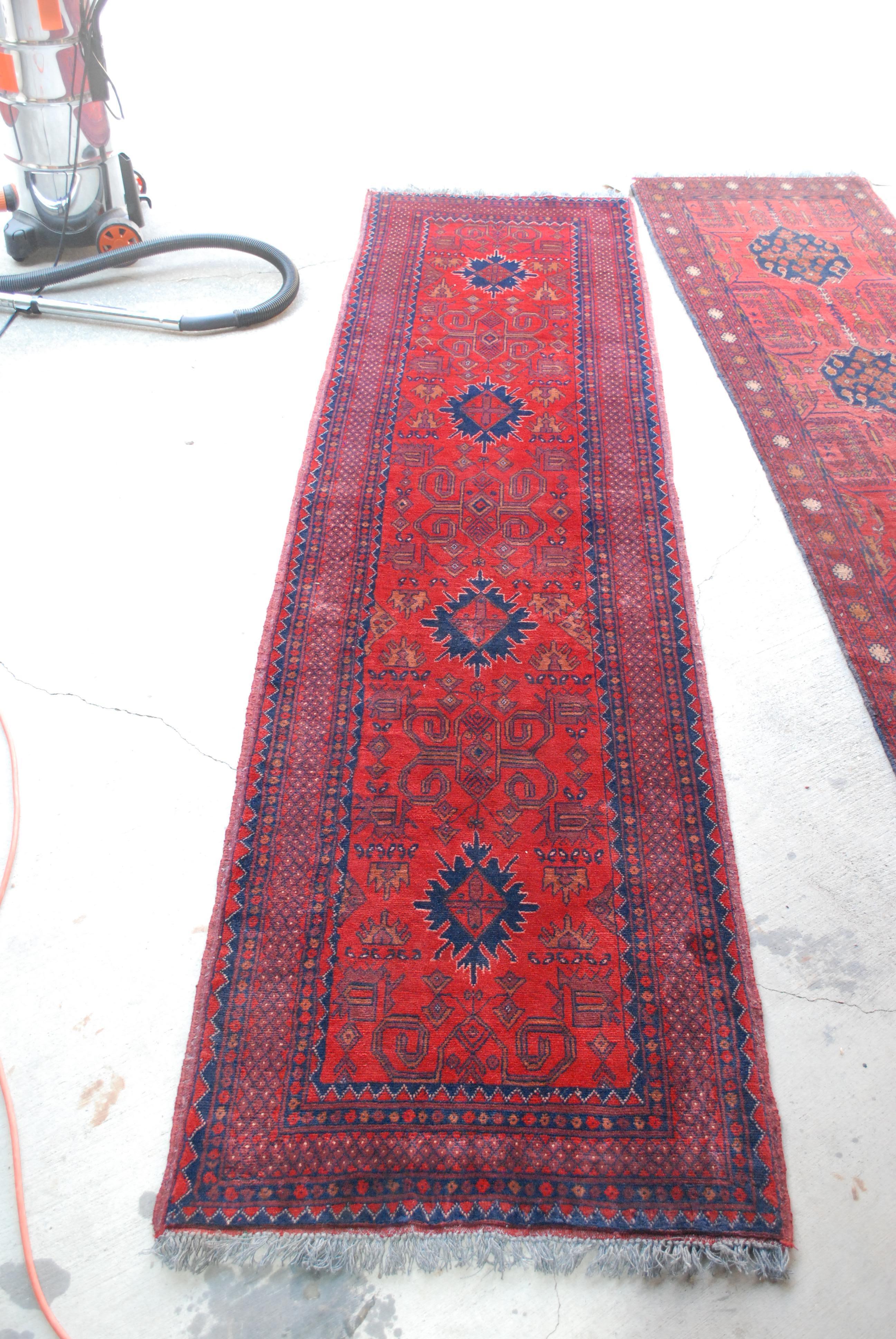 A Bohemian low-pile wool runner in rust, reds and blue accents. hand knotted wool. Symmetrical design, great vintage condition.