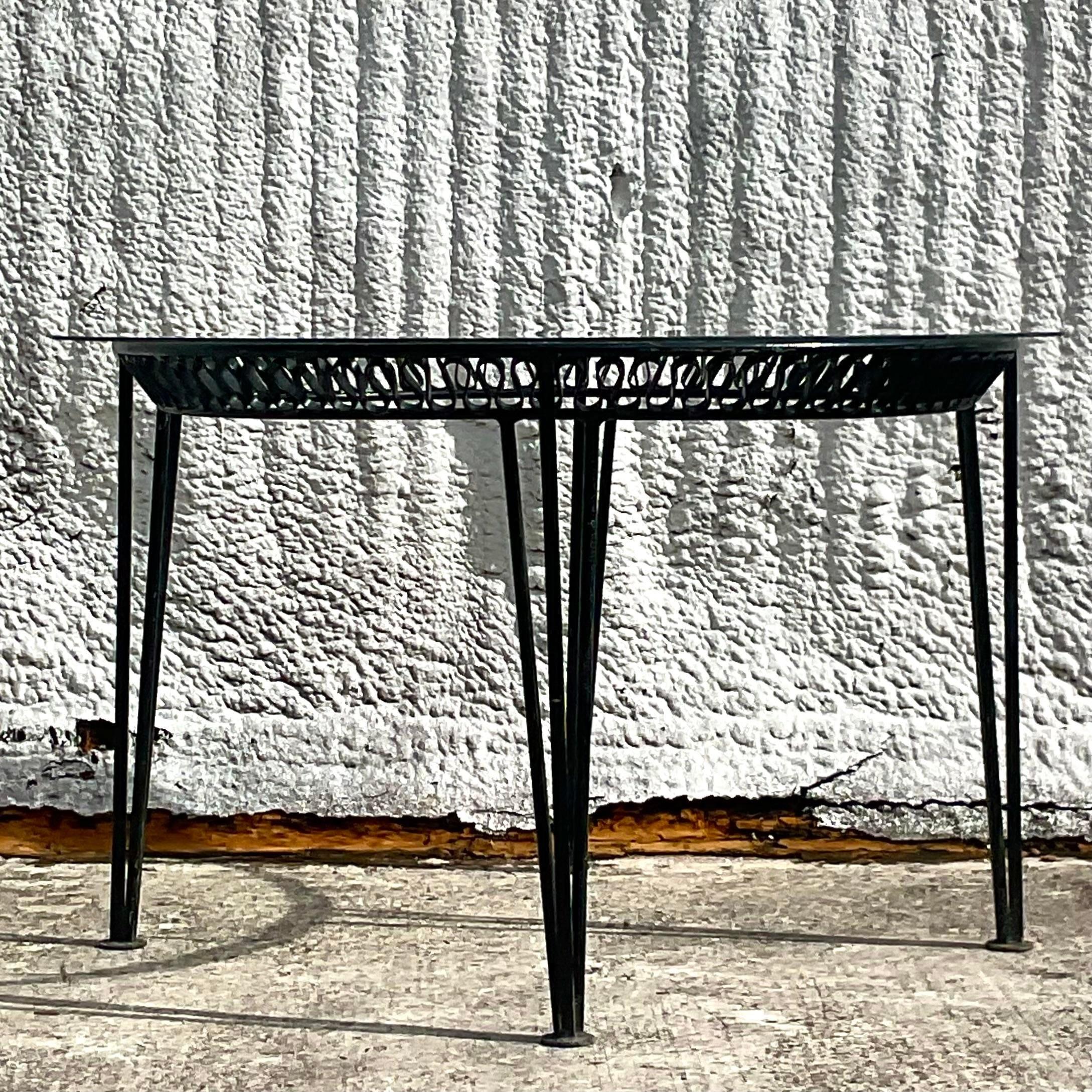 An incredible set of six vintage MCM outdoor dining chairs. Made by the iconic Salterini group. Unmarked. A solid wrought iron in a glossy black finish. The coveted ribbon design with bands along the back of the chairs two arms and four sides.