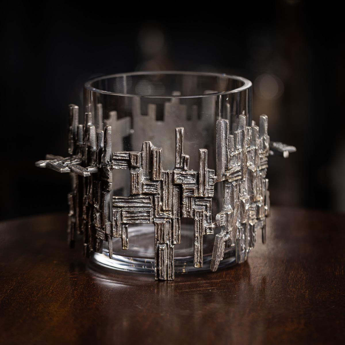 A 20th Century silver plated Brutalist style ice bucket, dating to the latter part of the 1960s. The ice bucket is made from glass and set in a silver plated rough hewn designed basket. An extremely elegant and very refined piece of interior