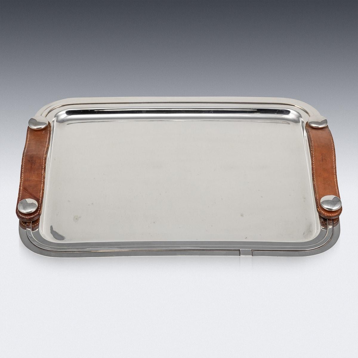 A Vintage 20th Century silver plated tray designed and retailed by the renowned fashion house Hermès, Paris. Of a rectangular shape featuring button style plated attachments with leather handles. Stamped into the leather, 