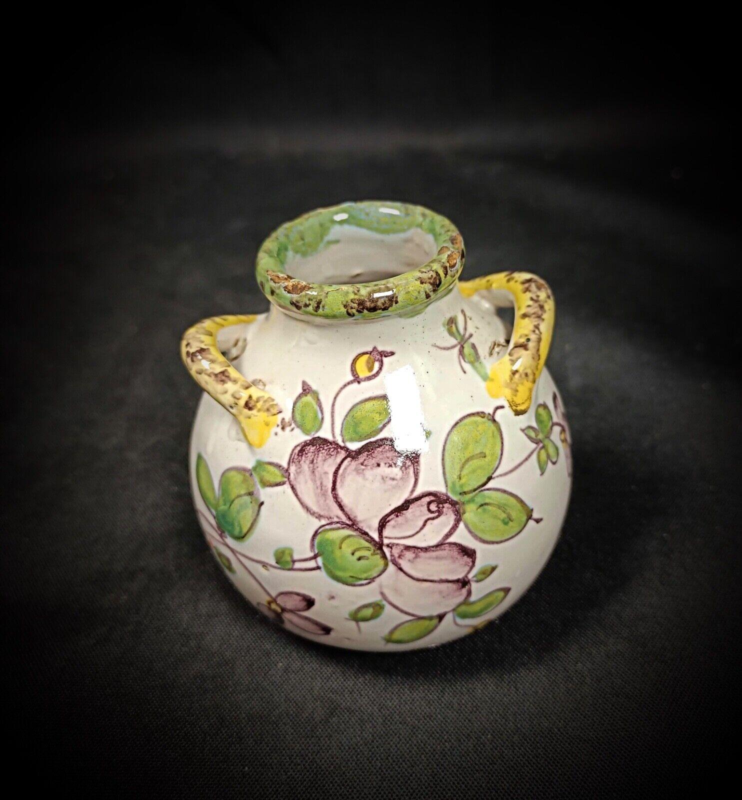 Questo incantevole vasetto vintage del XX secolo è realizzato in terracotta smaltata e presenta un delicato disegno floreale. Il vaso è in buone condizioni generali, con alcune piccole macchie e una crepa sul lato inferiore, come mostrato nelle