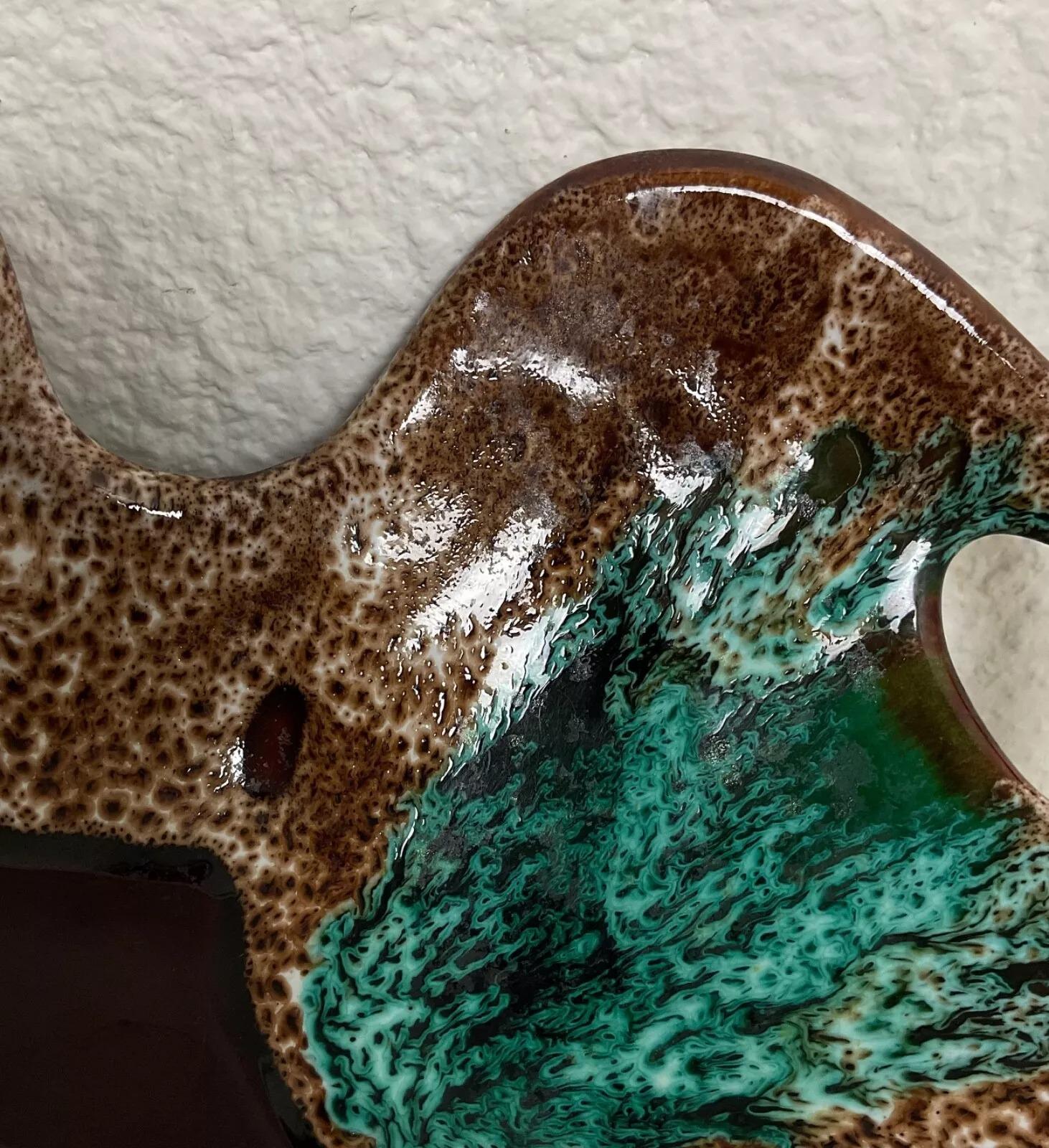 Ce plat en céramique vintage du XXe siècle de Vallauris est une pièce unique et artistique, alliant fonctionnalité et artisanat. Mesurant 7,5 cm de haut, 37 cm de long et 24,5 cm d'épaisseur, cet élégant plat pèse 1,255 kg. Sa glaçure vibrante et