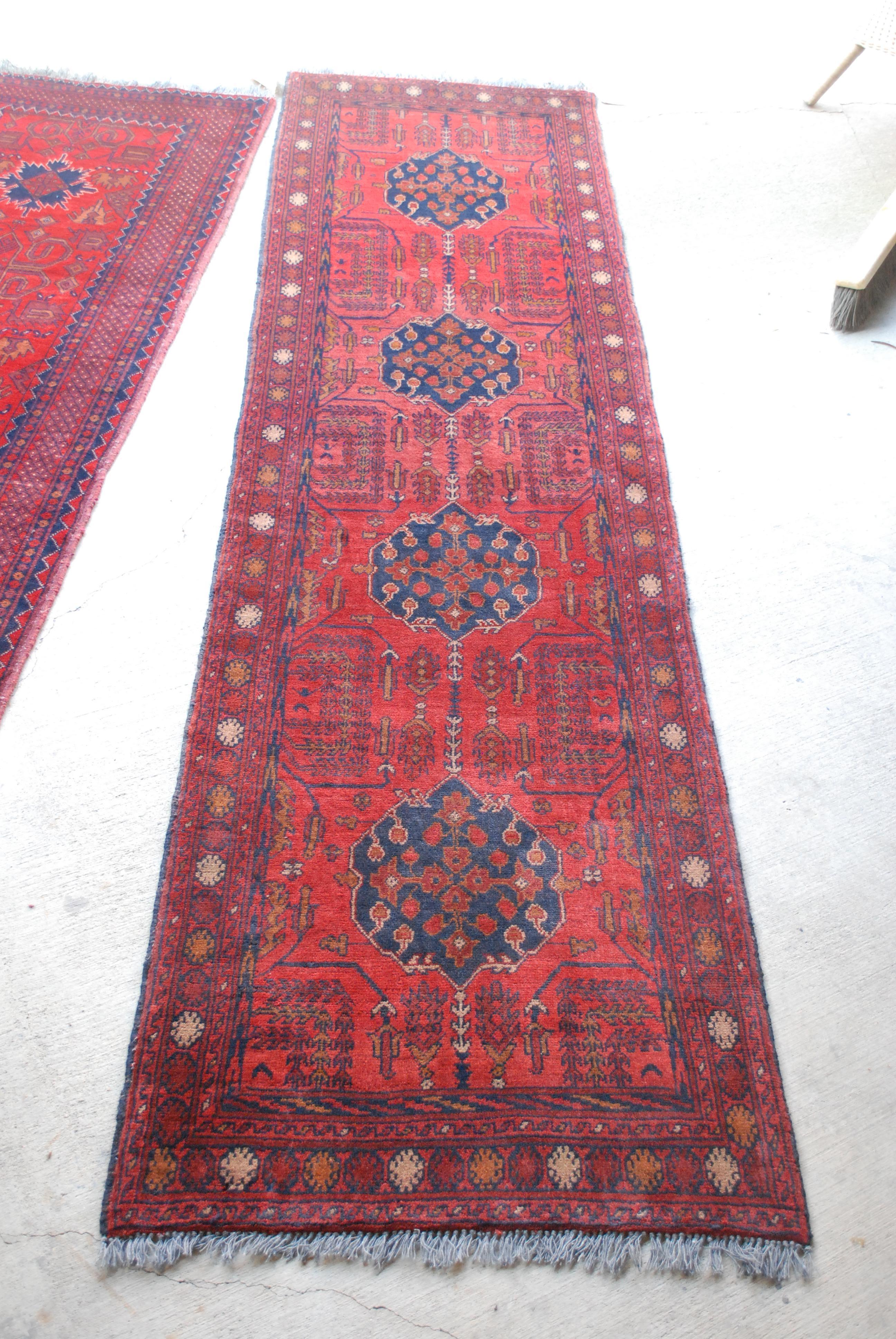 A Bohemian low-pile wool runner in rust, reds and blue accents. Hand knotted wool. Symmetrical design, great vintage condition.