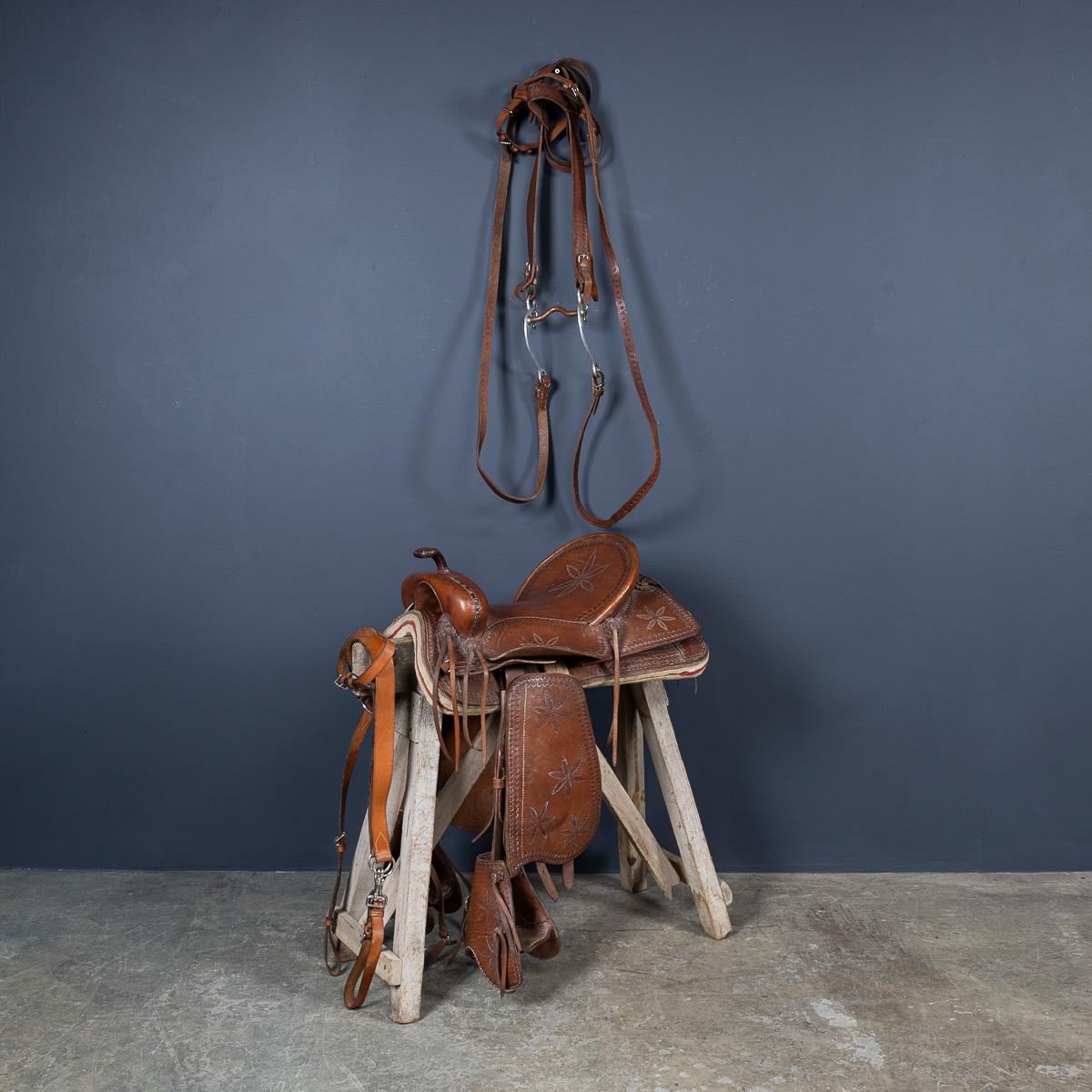 Selle de cheval western du 20e siècle en cuir estampé, avec des motifs complexes autour du siège et des courroies. La selle est équipée de pare-chocs, d'une martingale et d'une bride, tous fabriqués dans un cuir tolélé assorti.

CONDITION
Dans