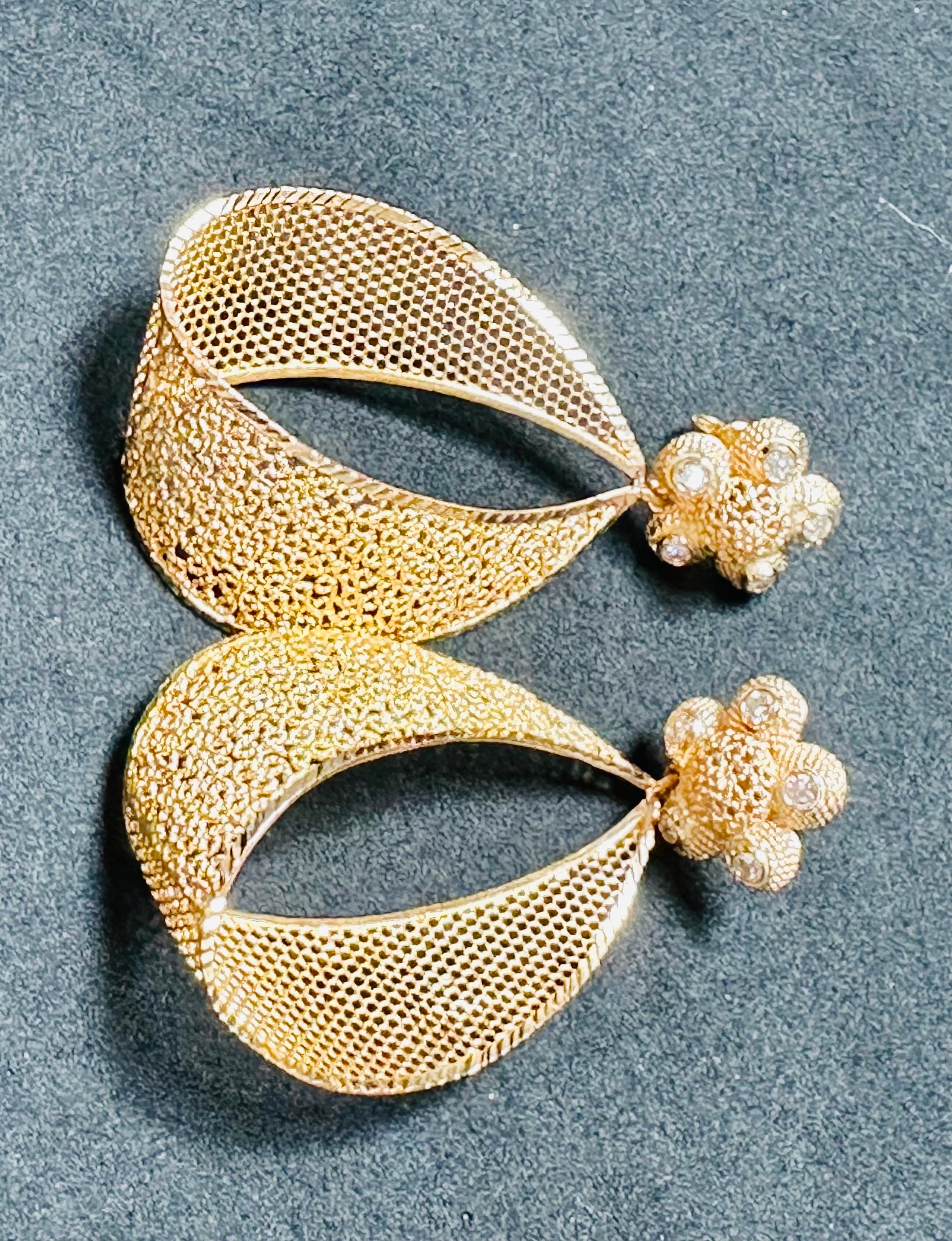 Introducing our exquisite Vintage 21 Karat Yellow Gold Dangling Earrings, a true statement piece adorned with diamonds. These stunning earrings feature a beautiful cut-out net design, adding an elegant touch to their overall aesthetic.

Crafted with