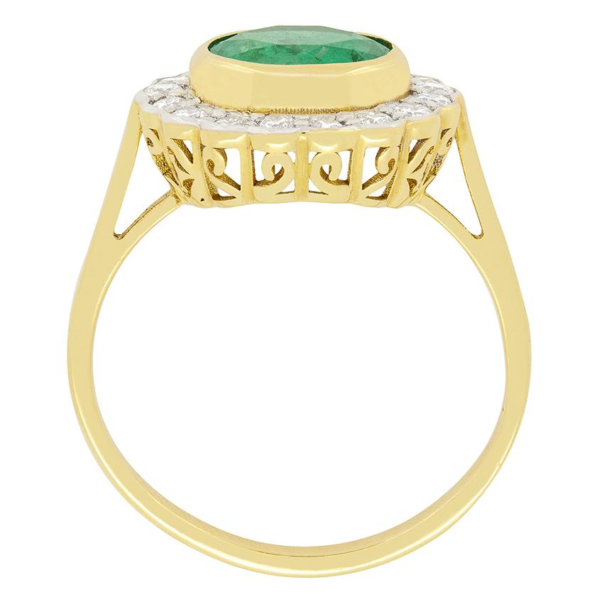 Dieser Halo-Ring im Vintage-Stil ist ein echtes Schmuckstück mit einem atemberaubenden Smaragd von 2,10 Karat im Rundschliff, der in der Mitte in 18 Karat Gelbgold gefasst ist. Dieser zentrale Stein ist von sechzehn runden Diamanten im