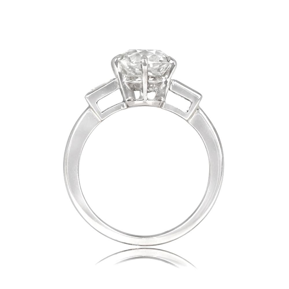 This engagement ring boasts a prong-set old European cut diamond center stone, weighing 2.14 carats with K color and VS1 clarity. The center stone is accompanied by two prominent baguette-cut diamonds. Hand-crafted in platinum, this ring dates back
