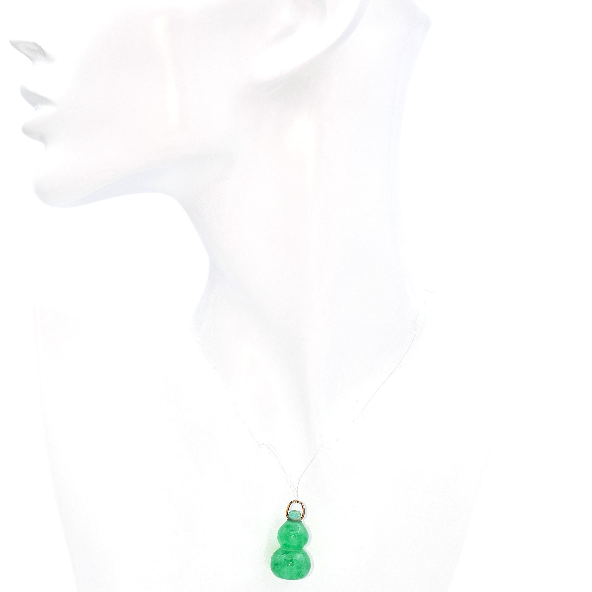 Explore the serene beauty of this Jade Pendant. The pendant is shaped like a double gourd, symbolizing abundance and harmony, and is made from vibrant green jade. A simple yellow gold loop elegantly secures the pendant, adding a touch of warmth and