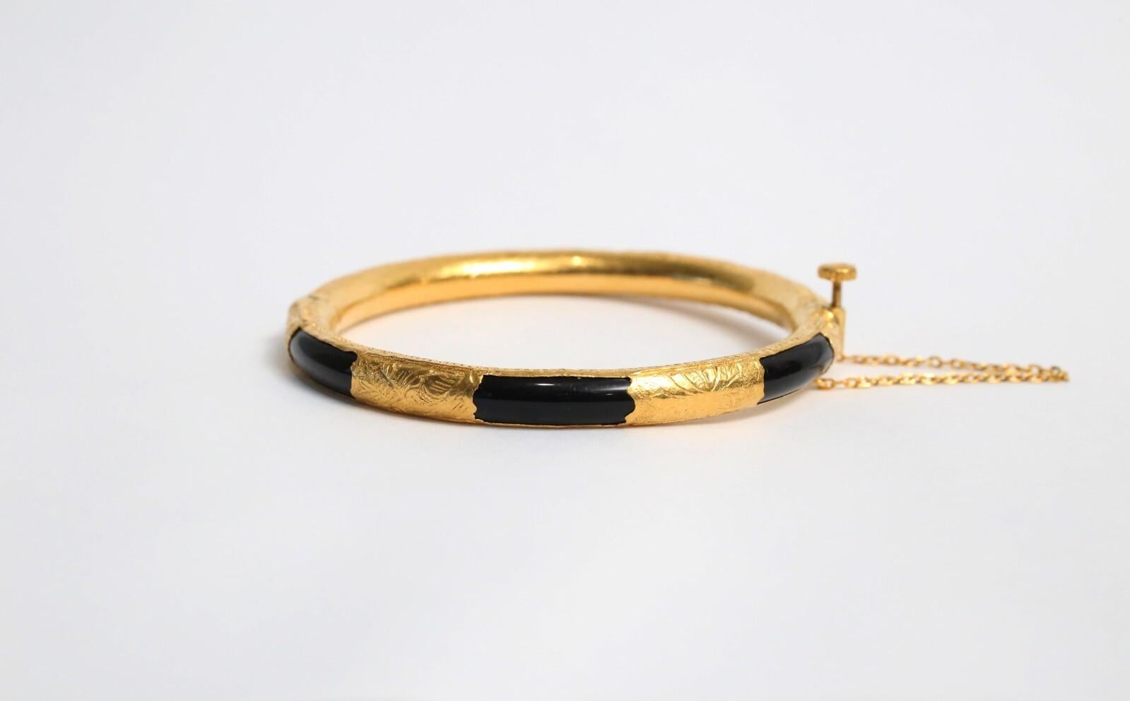 Este brazalete chino vintage está elaborado en rico oro amarillo de 21 quilates y presenta segmentos alternados de jade negro, creando un sorprendente contraste entre luz y oscuridad. Las secciones de oro están adornadas con intrincados grabados