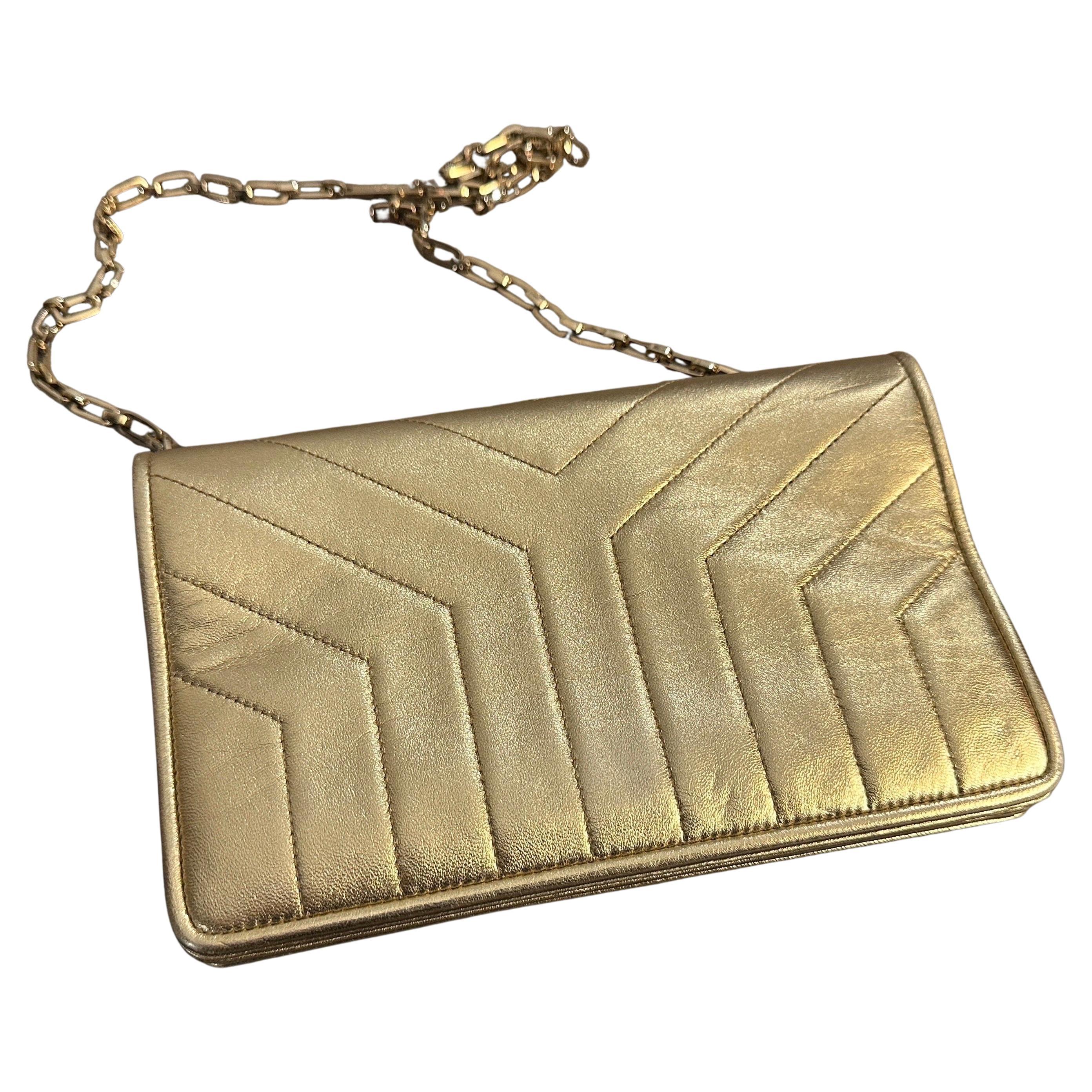 This is a vintage Yves Saint Laurent (YSL) handbag in metallic gold leather. It features a structured rectangular silhouette with elegant chevron quilted stitching, which adds depth and sophistication to its design. The gold-tone chain strap is