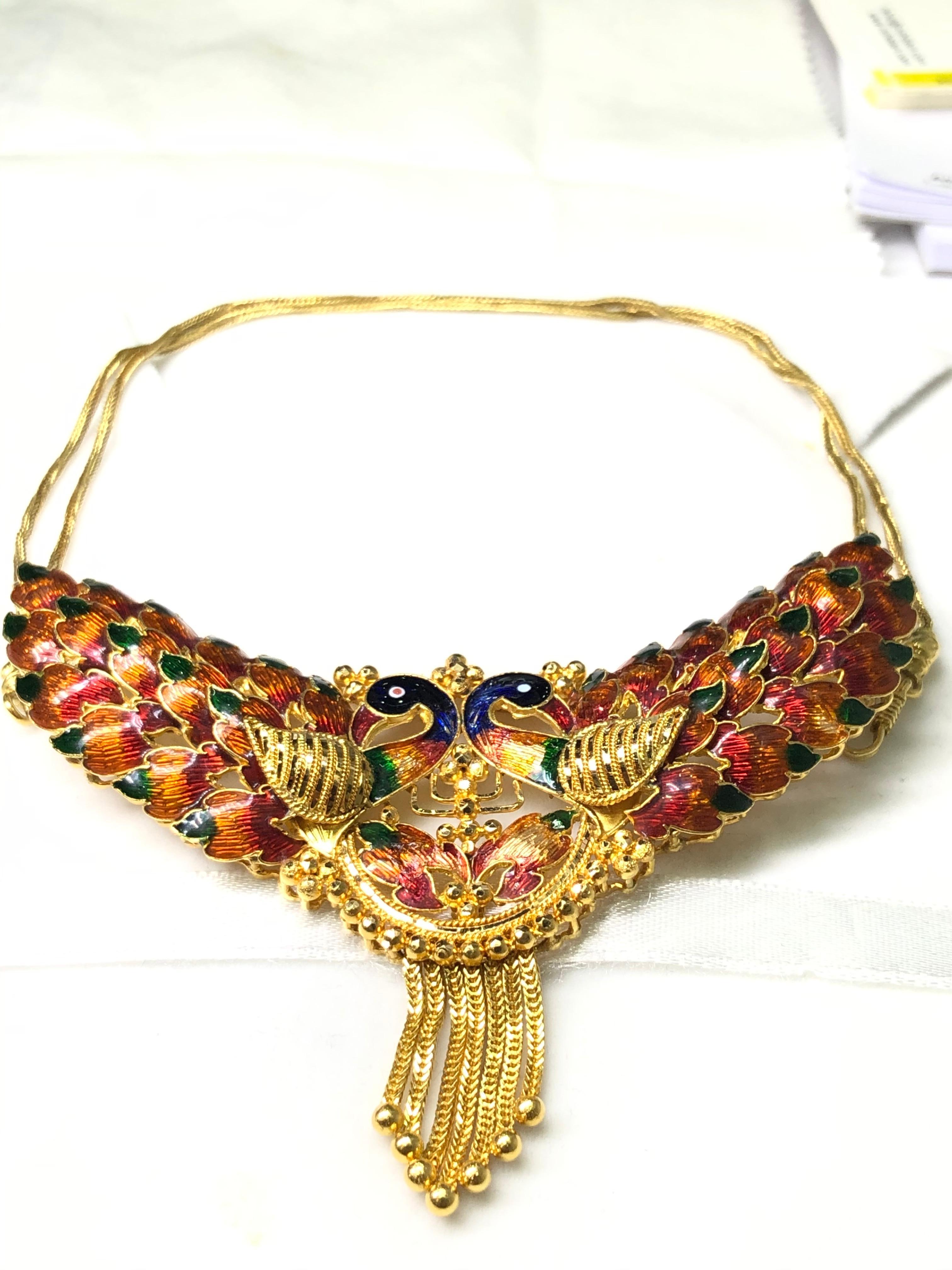 This necklace hand made in India and forged in 22 karat gold features bright colors and detailed enamel work bringing the peacock imagery to life.