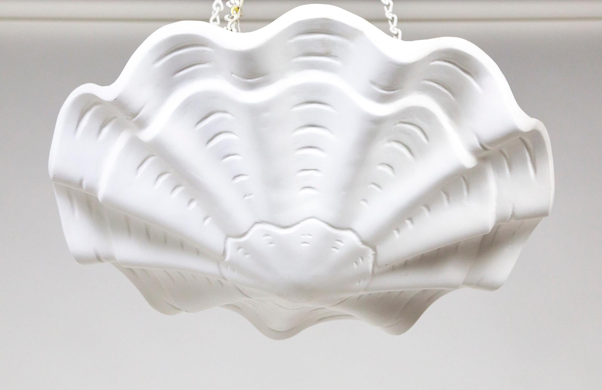 A plaster pendant in an undulating shell shape, with scalloped edges and imprinted lines accentuating the form. Made by Phoenix Day of San Francisco in the 1970s. The original canopy is a decorative gadrooned finial. A newer take on Francis Elkins's