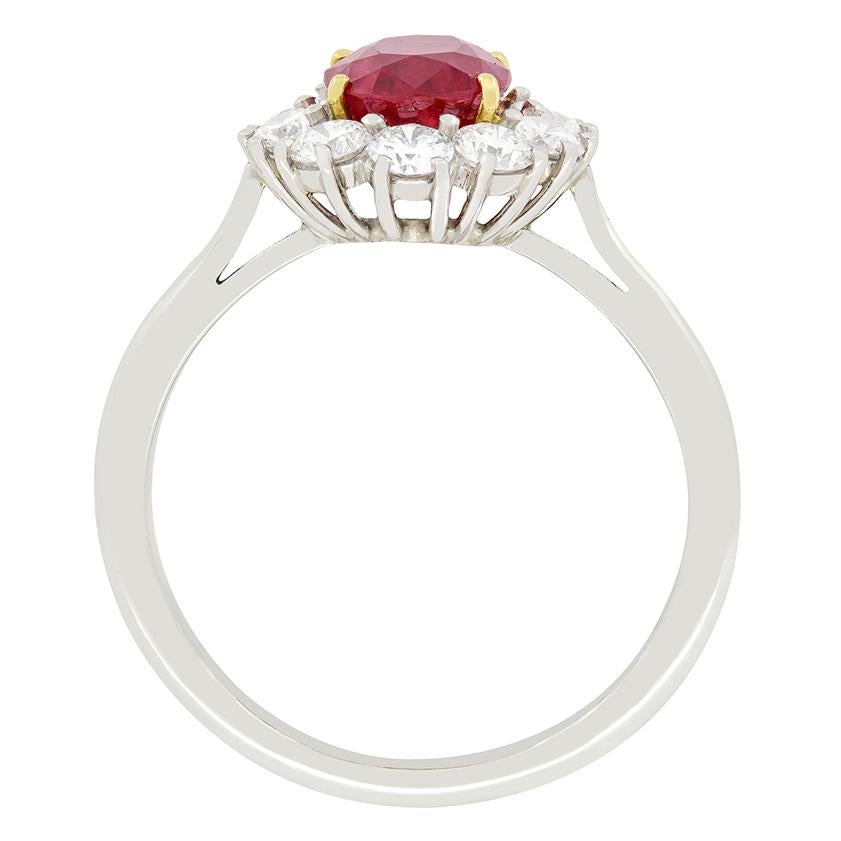 A vivid red ruby oval cut ruby is surrounded by a diamond halo in this vintage cluster ring. Certified by the Gem and Pearl Labs, the ruby has been confirmed to be of Thai origin, completely natural and unheated. The 2.20 carat ruby's intense colour