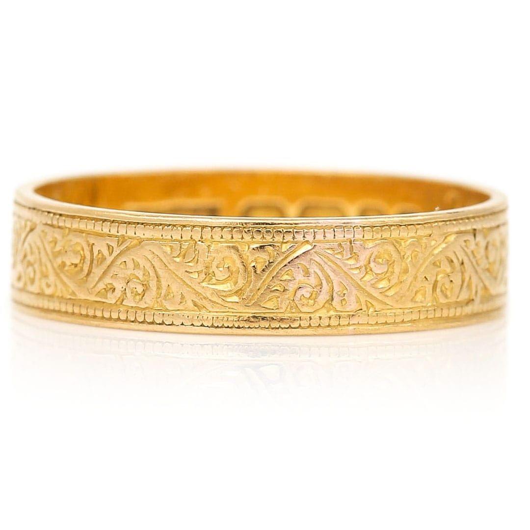 A stylish vintage 22ct yellow gold foliate engraved wedding band ring dating from circa 1968. This unique mid 20th century band is engraved with a floral design around the centre of the band boarded by a millegrain edge. British in origin the sweet