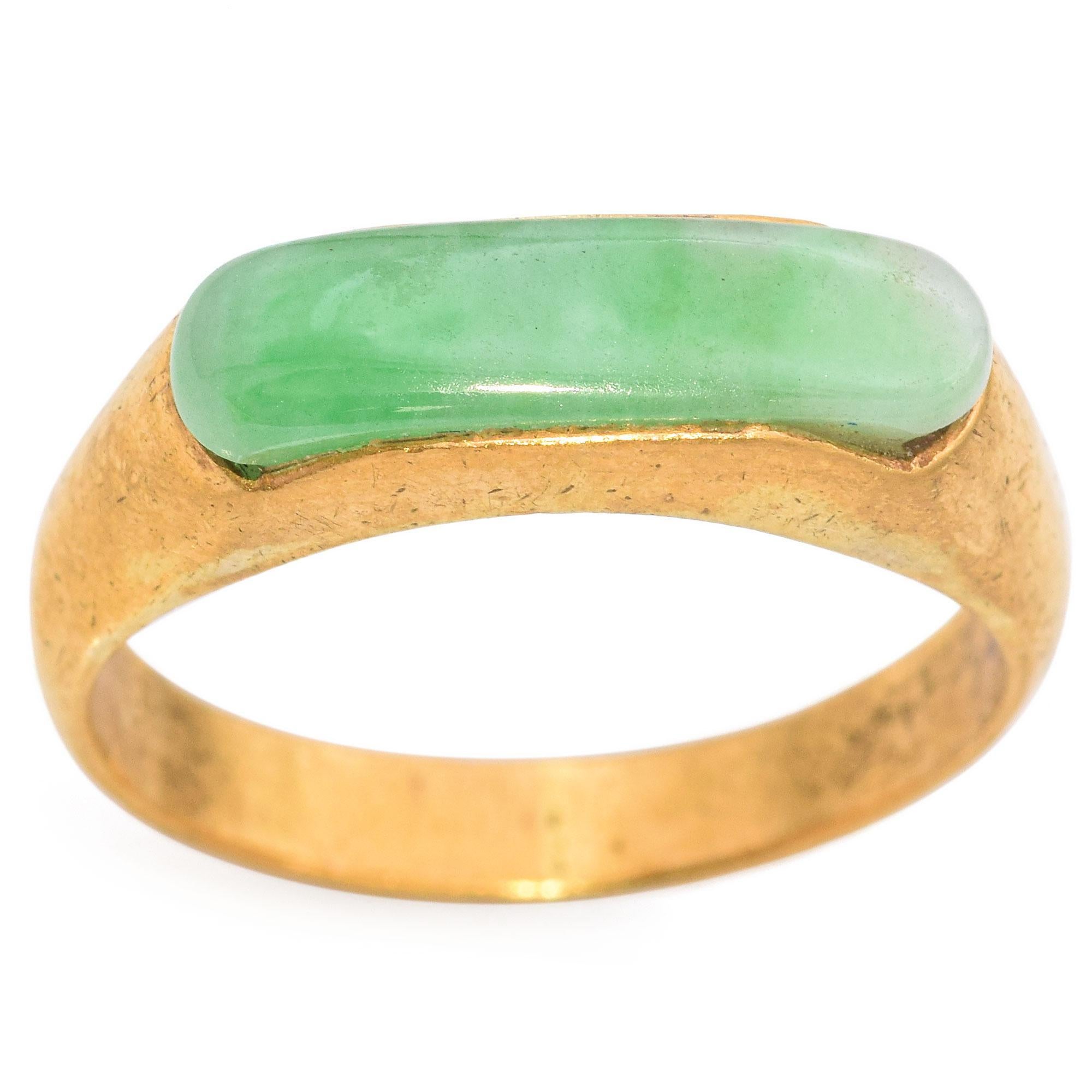 A refined and elegant vintage ring featuring a 1.07 carat elongated cabochon-cut green jade.
The jade is set in a sleek band of 22k yellow gold, highlighting its natural beauty.
The jade has a smooth, polished surface with subtle variations in