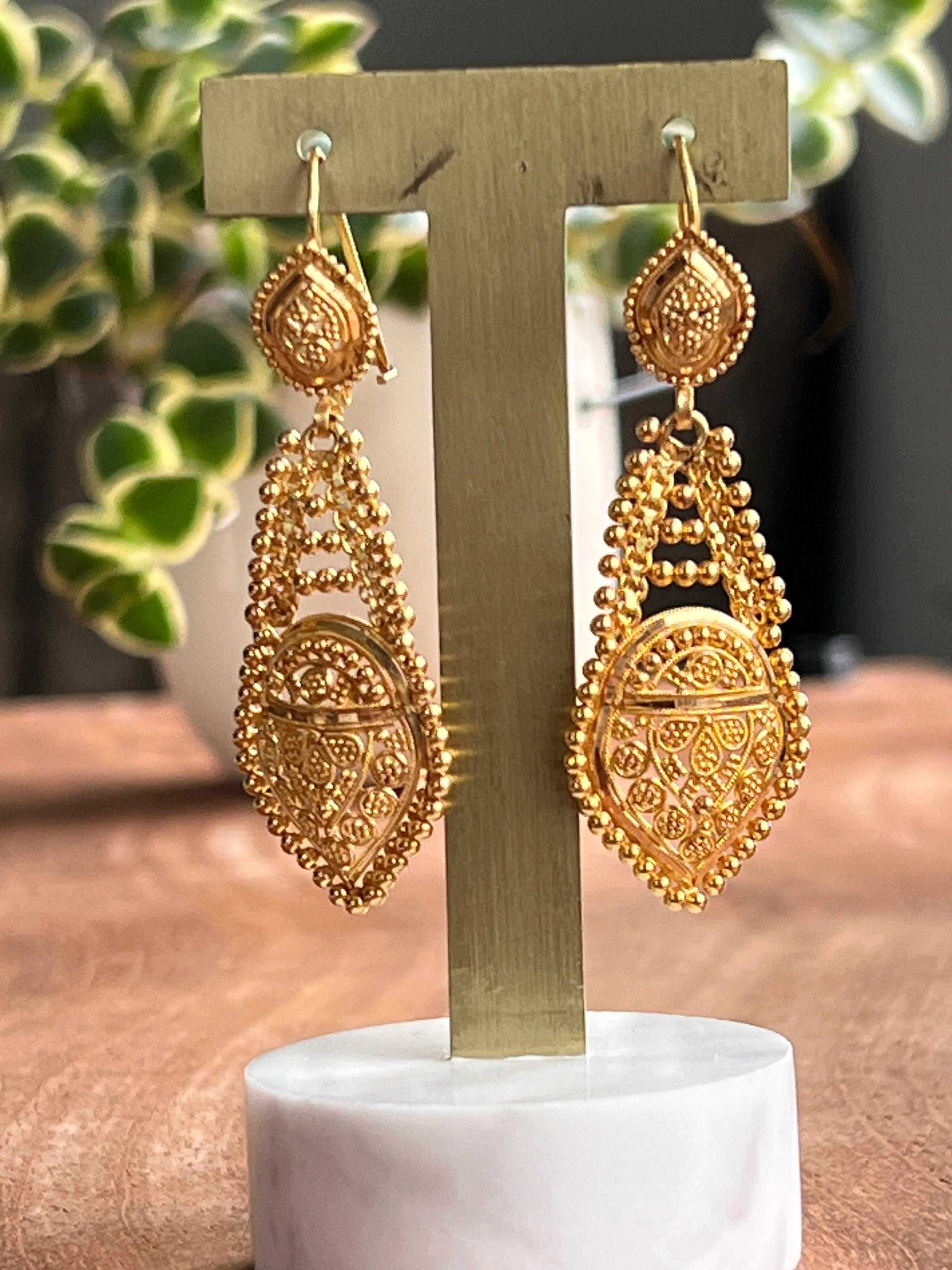 Questi straordinari orecchini vintage a pendente, realizzati negli anni '70, sono in oro giallo 22 carati e presentano dettagli in filigrana. Ogni orecchino presenta un motivo a goccia ornato da una fine granulazione e da un'ornamentale lavorazione