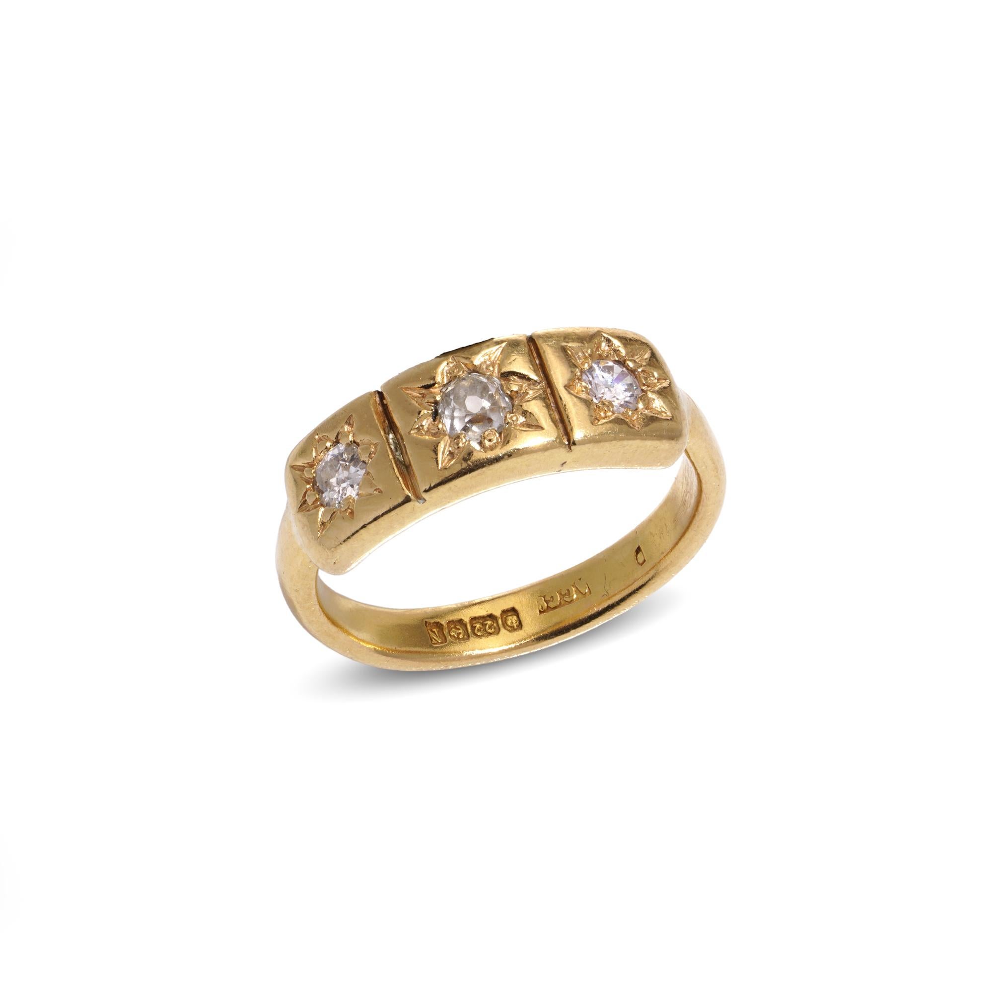 This is a vintage three-stone diamond ring crafted from 22-karat yellow gold. The diamonds are elegantly set in a star-setting arrangement. It was made in Birmingham, England, in late 1937, and it bears a full hallmark, including the maker's mark