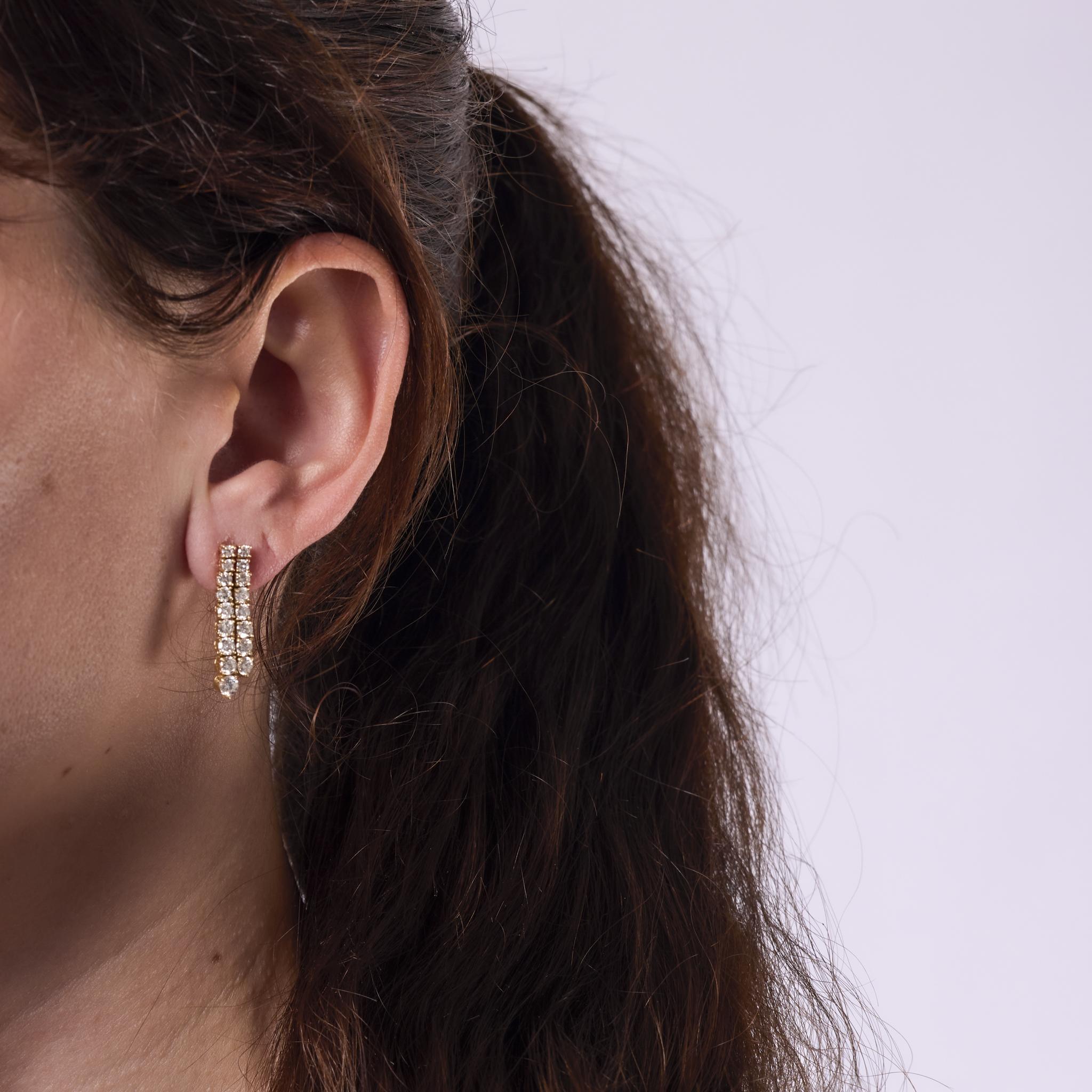 These vintage earrings from the 1990s are crafted in 18k yellow gold and feature 34 round brilliant cut diamonds totaling approximately 2.30 carats. The diamonds are graded F color and SI clarity, offering bright, elegant sparkle in a classic form.