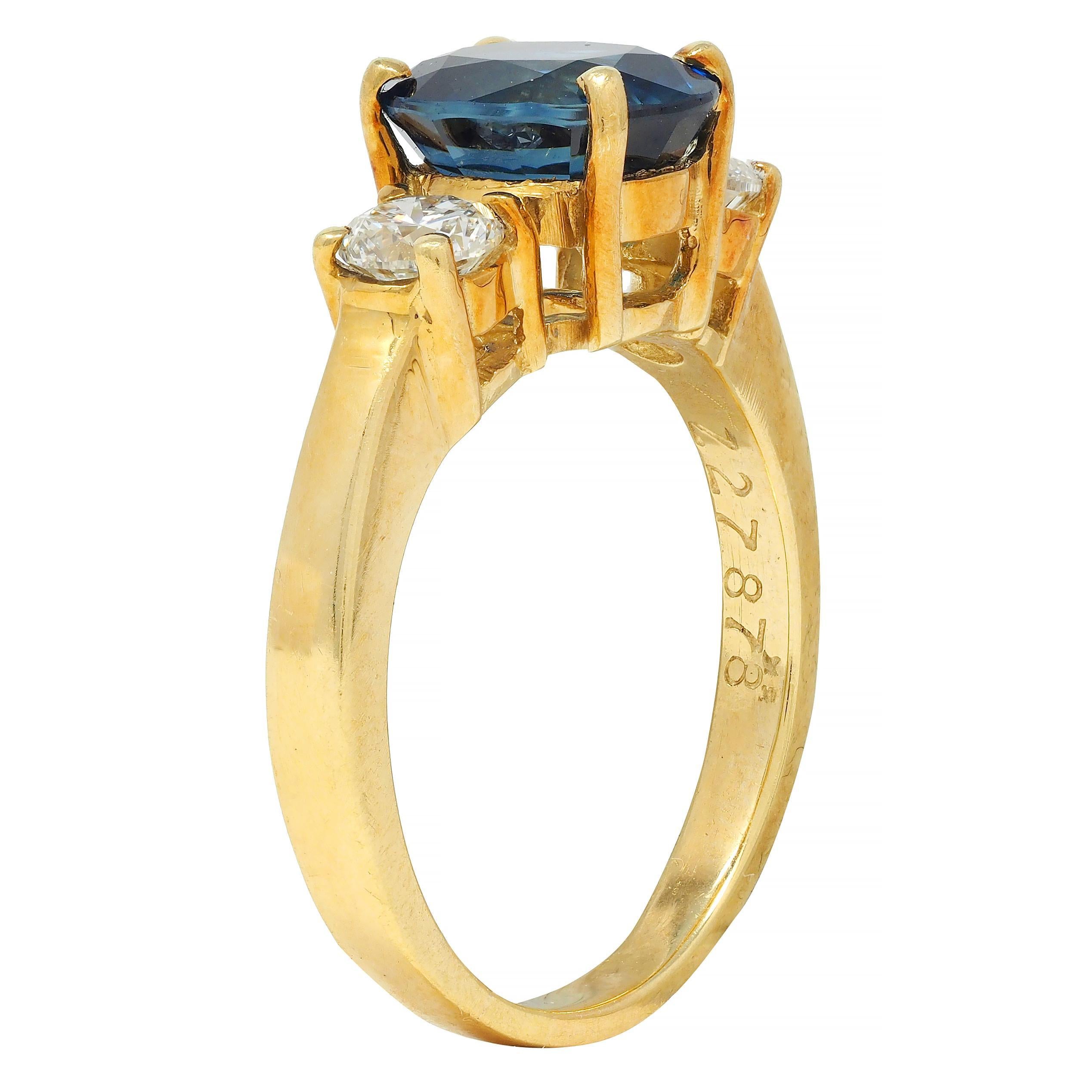 Centering an oval cut sapphire weighing 1.86 carats total - transparent deep blue in color 
Natural Thai in origin - prong set in basket and flanked by prong set diamond shoulders
Weighing approximately 0.46 carat total - G color with VS2 to SI1