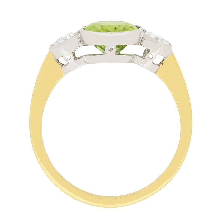 This striking vintage ring features a 2.40 carat peridot with a diamond on each side. The oval cut peridot is a vibrant olive green colour, and is rub over set in 18 carat white gold. The diamonds are 0.40 carat each, and are I colour and VS