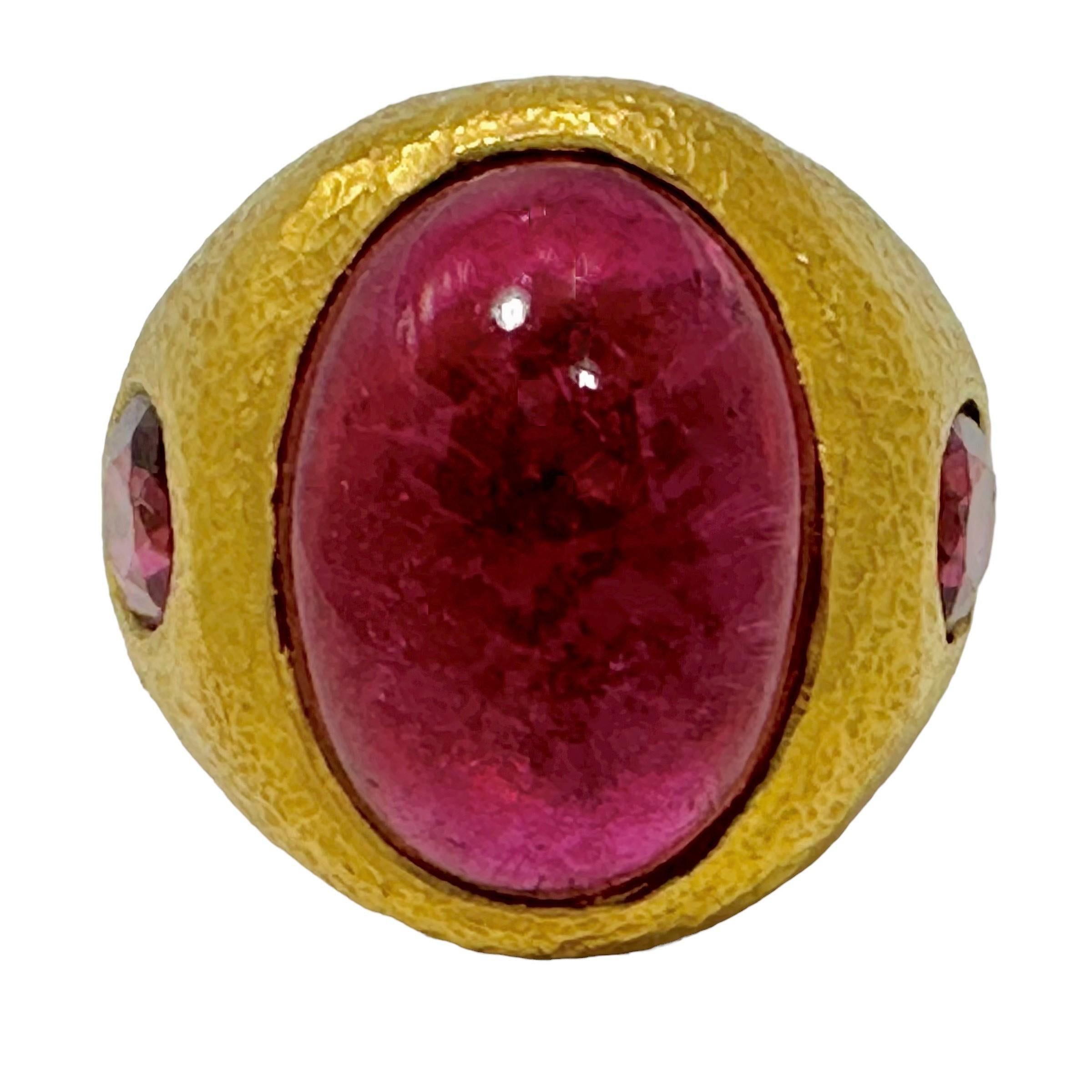 This luxurious classic revival ring is fashioned from pure 24K gold and  has a very finely hand hammered finish over all forward surfaces. Expertly bezel set is a rich red 18mm x 14mm Rubellite Tourmaline cabochon weighing approximately 11.00ct,