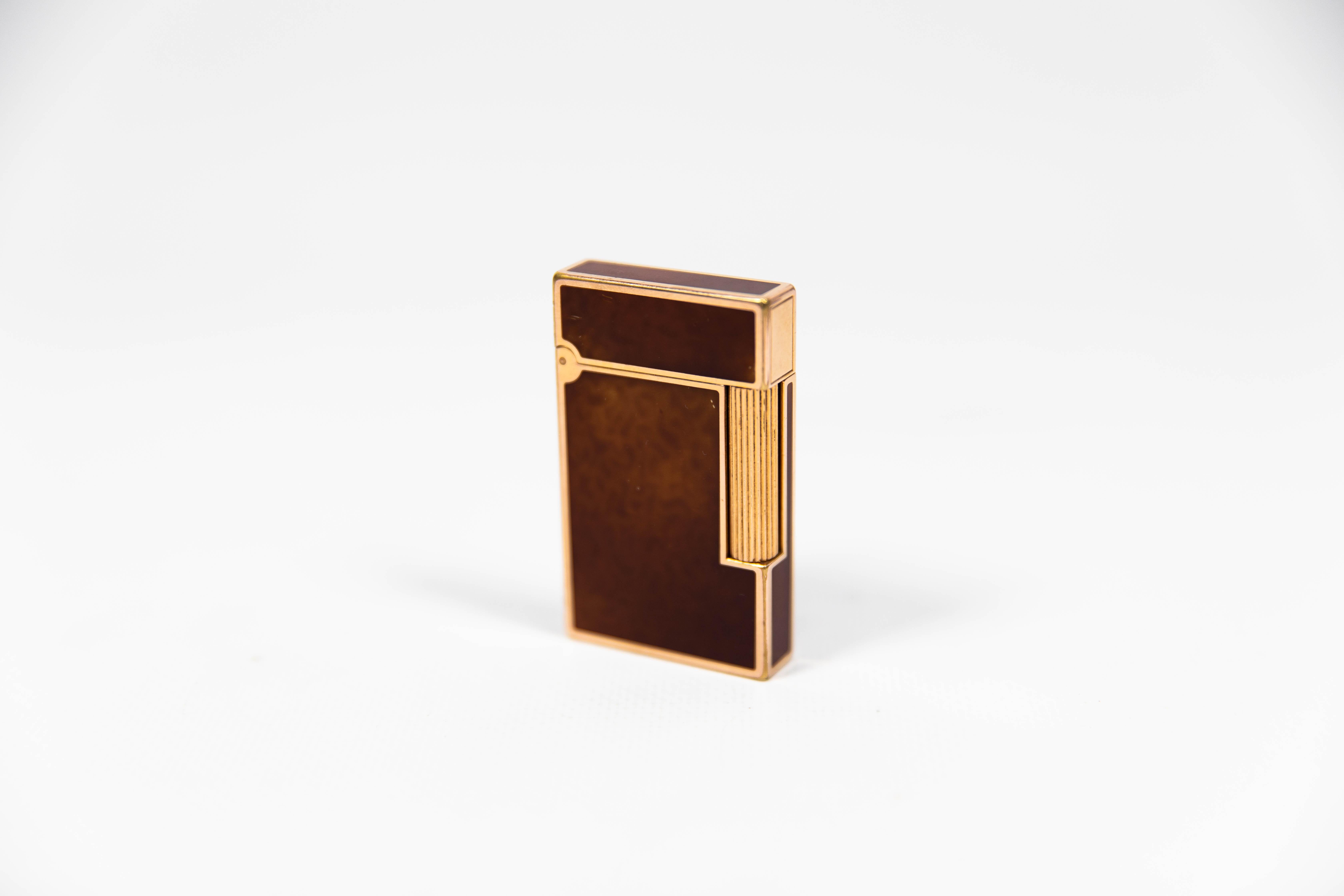 Vintage Authentic 24k Gold plated Ligne 2 ST Dupont Lighter in fire-brown Lacquer 1990s 

The iconic S.T. Dupont name is known for quality, well-made cigarette lighters and other luxury implements. The company’s origin can be traced to Simon