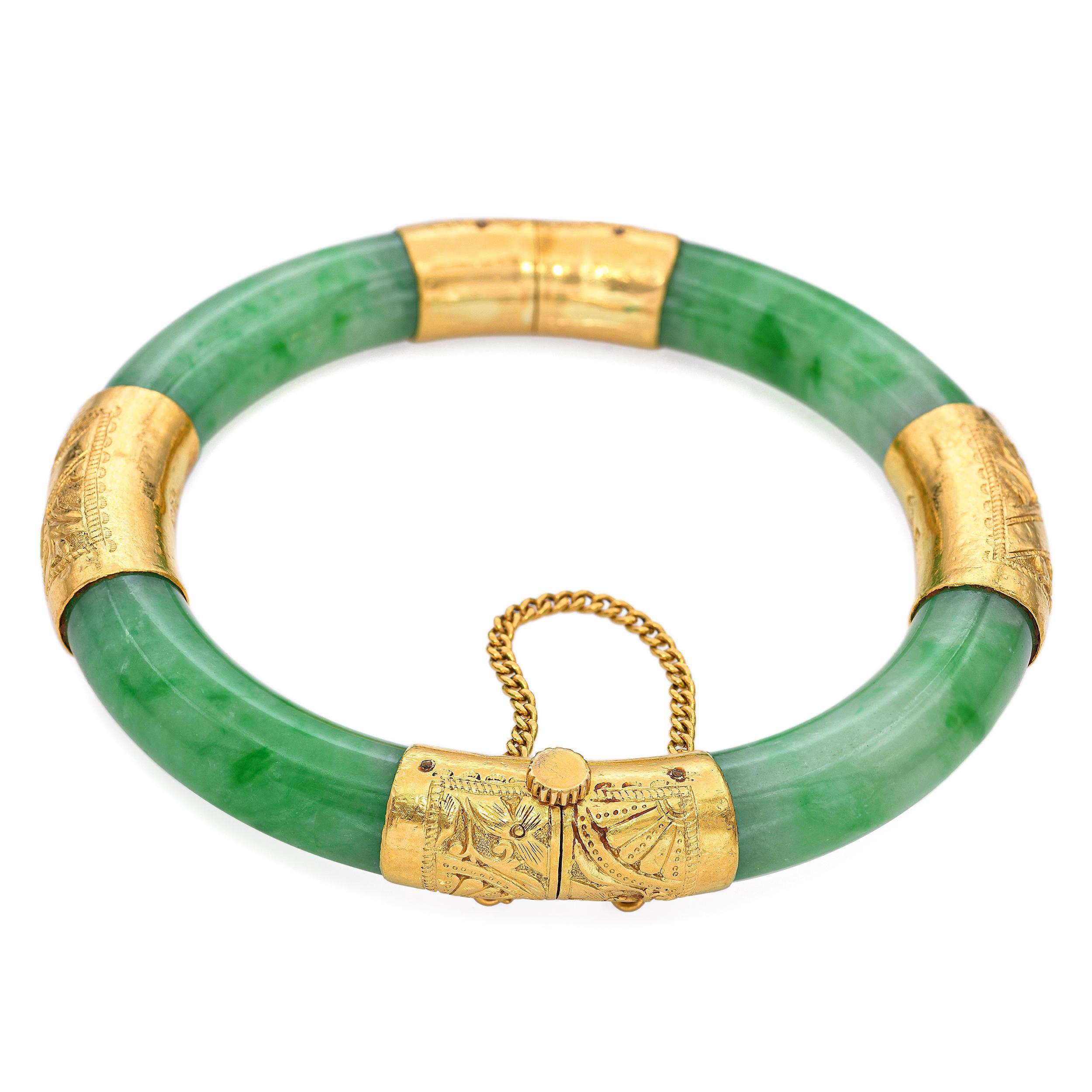 Una llamativa pulsera brazalete vintage elaborada en rico oro amarillo de 24 quilates y engastada con una suave banda de jade pulido. La pulsera tiene un diseño articulado que facilita su uso, y muestra un equilibrio de jade verde vibrante y oro