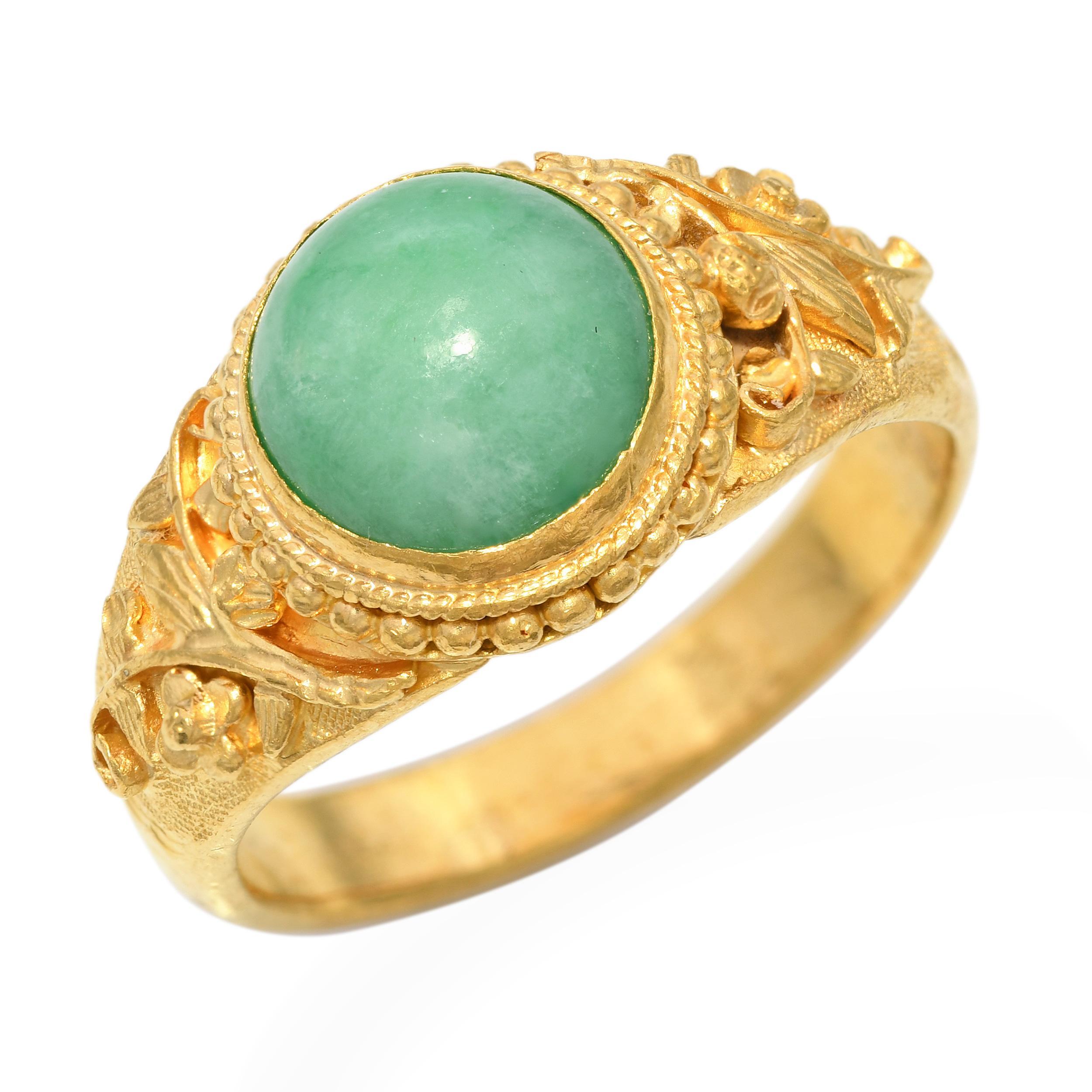Cette bague vintage présente une magnifique pièce de jade naturel en forme de dôme, s'élevant doucement de sa riche monture en or jaune 24k. La teinte vert tendre du jade se marie élégamment à l'éclat chaud de l'or pur, conférant à la pièce un