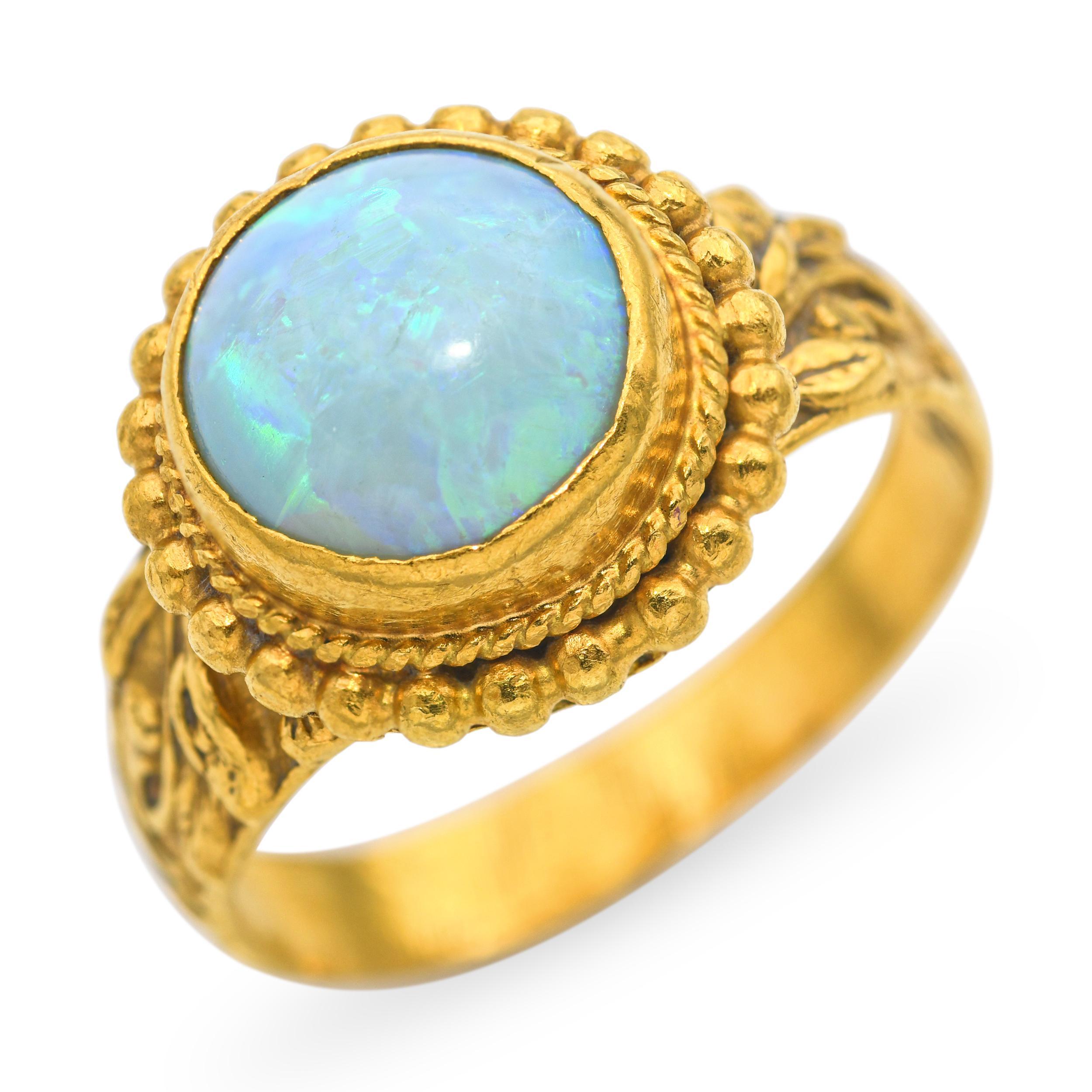 Questo squisito anello vintage è realizzato in puro oro giallo 24k e presenta un'affascinante opale naturale con vividi giochi di colore blu e verde. Le sfumature scintillanti dell'opale si muovono meravigliosamente alla luce, offrendo un contrasto