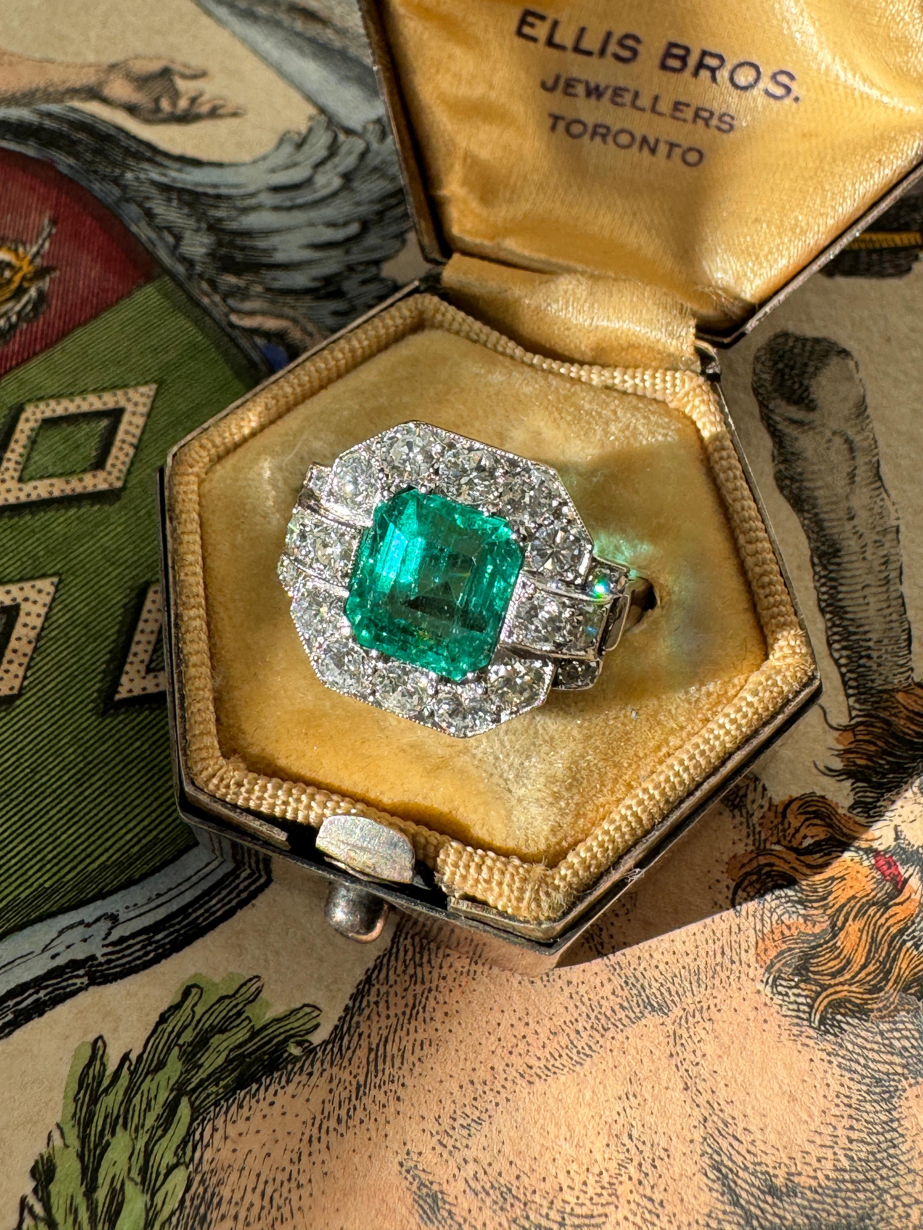A lush and lively octagonal step-cut Colombian emerald, weighing 2.5 carats, is elegantly presented in a frame of sparkling brilliant-cut diamonds. This low profile ring boasts gently rolled shoulders with a side gallery adorned with hand engraved
