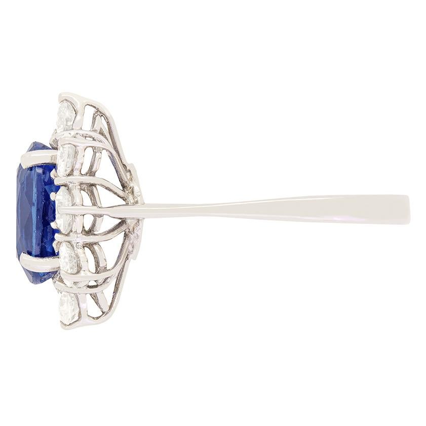This vintage cluster ring features a stunning 2.50 carat oval cut sapphire at its centre, encircled by a halo of round brilliant cut diamonds. The diamonds total 1.50 carat and have a colour of I and clarity of VS1. The gemstones are claw set into