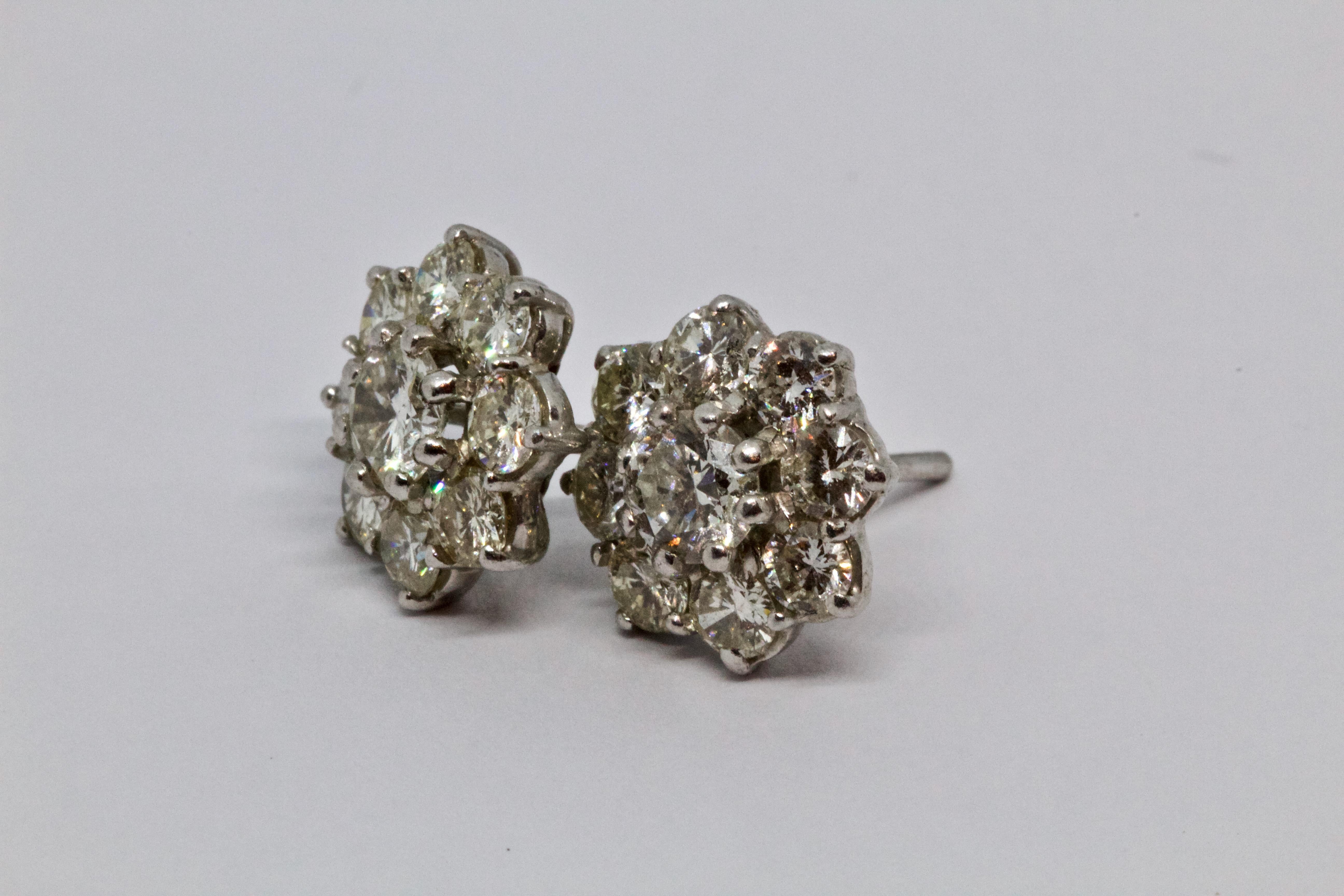 A flower-shaped cluster of round brilliant cut white diamonds that weigh a total of 2.6 carats, with scalloped edges and a lot of vintage charm. For she who desires a classic pair of earrings for daily wear, but does not want the monotony of plain