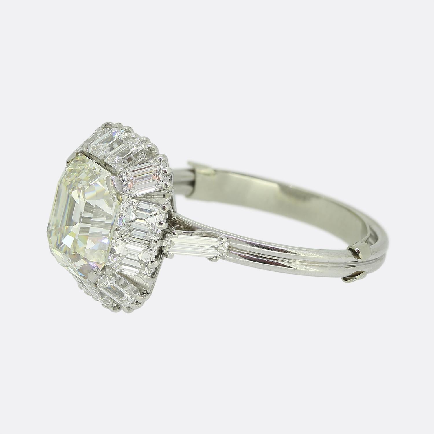 Here we have a stunning vintage diamond ring that has been crafted in platinum. The ring plays host to a central asscher cut diamond which is surrounded by twelve emerald cut diamonds set in a ballerina style. The angle of the surrounding stones
