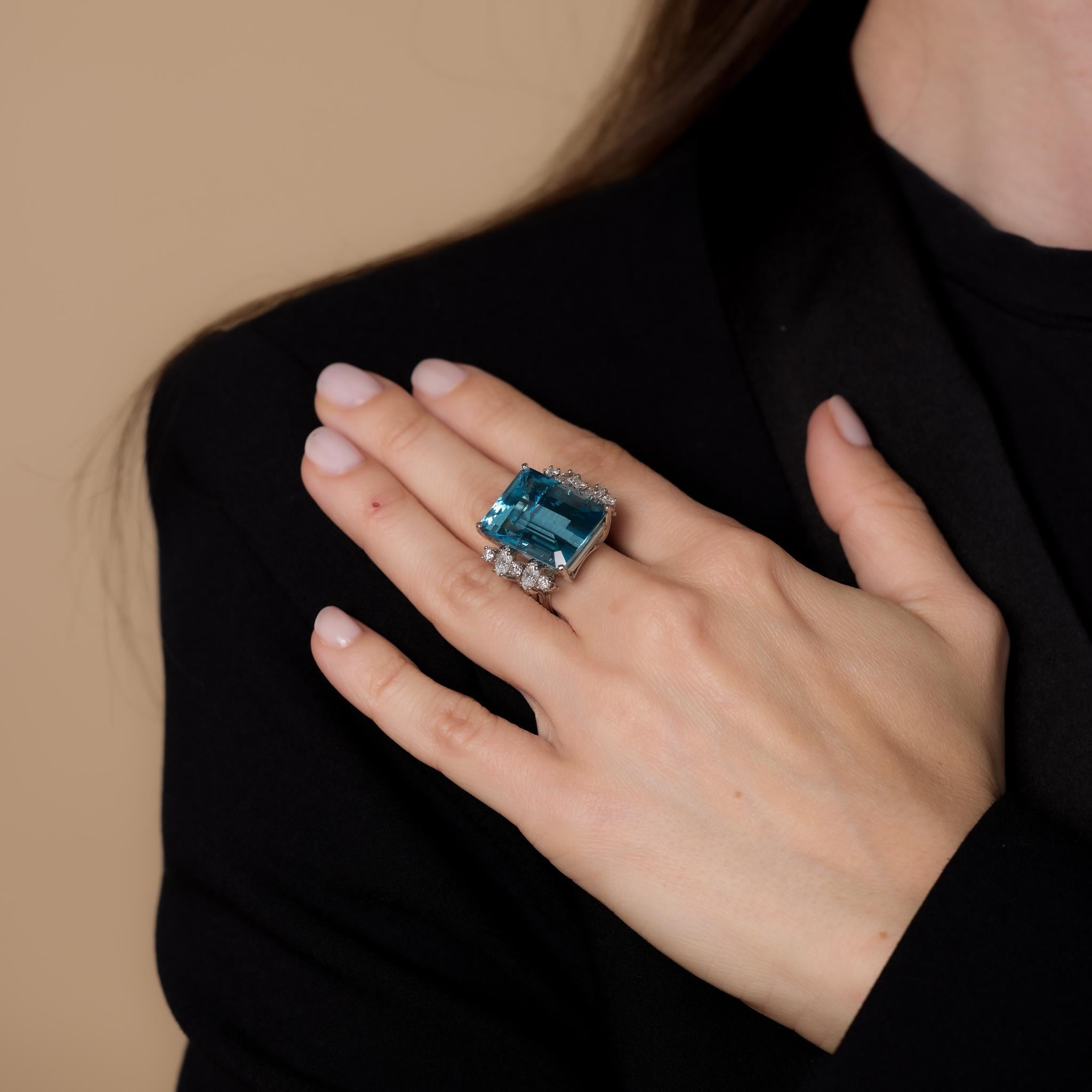This vintage platinum cocktail ring showcases a 26.41-carat emerald cut aquamarine, accented by four marquise and six round brilliant cut diamonds totaling approximately 1.20 carats, D-E color, and VS clarity. Crafted in the 1980s, it weighs 18.61
