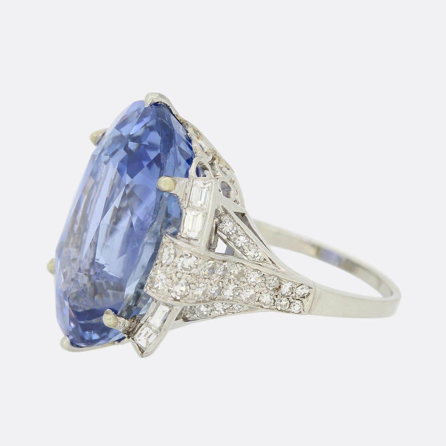 This is a wonderful sapphire and diamond ring from the 1950s period. The oval cut sapphire is untreated, of ceylon origin and a cornflower blue tone. It is a rare and impressive 26.93 carats and sits in a 6 clawed platinum mount. Each shoulder has