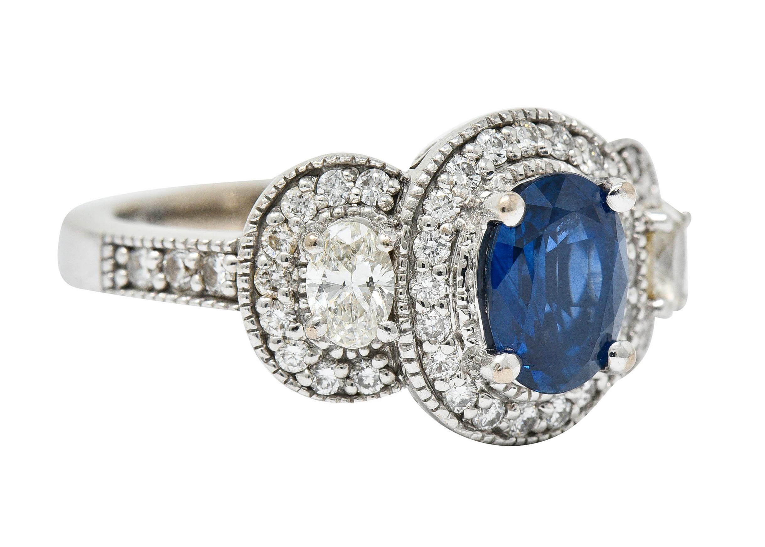 Ring is designed as three clusters comprised of diamond and milgrain surrounds

Centering an oval cut sapphire weighing approximately 1.50 carats - medium dark blue in color

Flanked by two oval cut diamonds weighing in total approximately 0.45