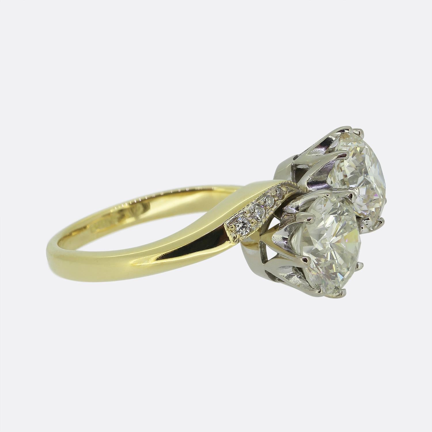 Hier haben wir einen schönen Kreuzring aus zwei Diamanten. Ein Duo runder Diamanten im Brillantschliff wurde einzeln in Weißgold in einer diagonalen Formation auf einem Band aus 18 Karat Gelbgold gefasst. Der Ring ist elegant mit vier kleineren