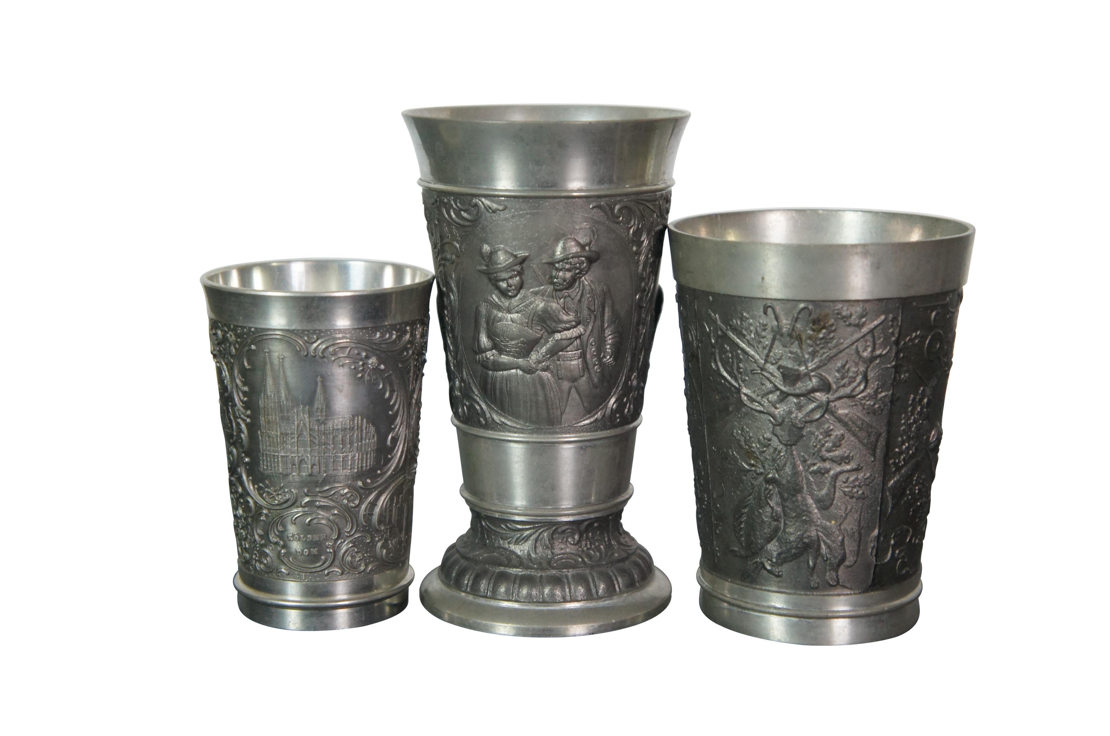 Lote de 29 copas/vasos de chupito alemanes de peltre/zinn vintage del siglo XX con diversos tamaños, motivos en relieve y fabricantes. Los diseños presentan motivos de tabernas bávaras / de la Black Forest, escudos heráldicos, temas de caza,