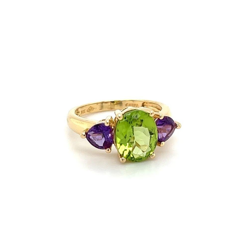 Simply Beautiful! Finely detailed Three Stone Oval Peridot and Heart Amethyst Gold Cocktail Ring. Centering a securely nestled Hand set 2.90 Carat Oval Peridot with Heart Amethyst, weighing approx. 0.90tcw on either side. Hand crafted 14K Yellow