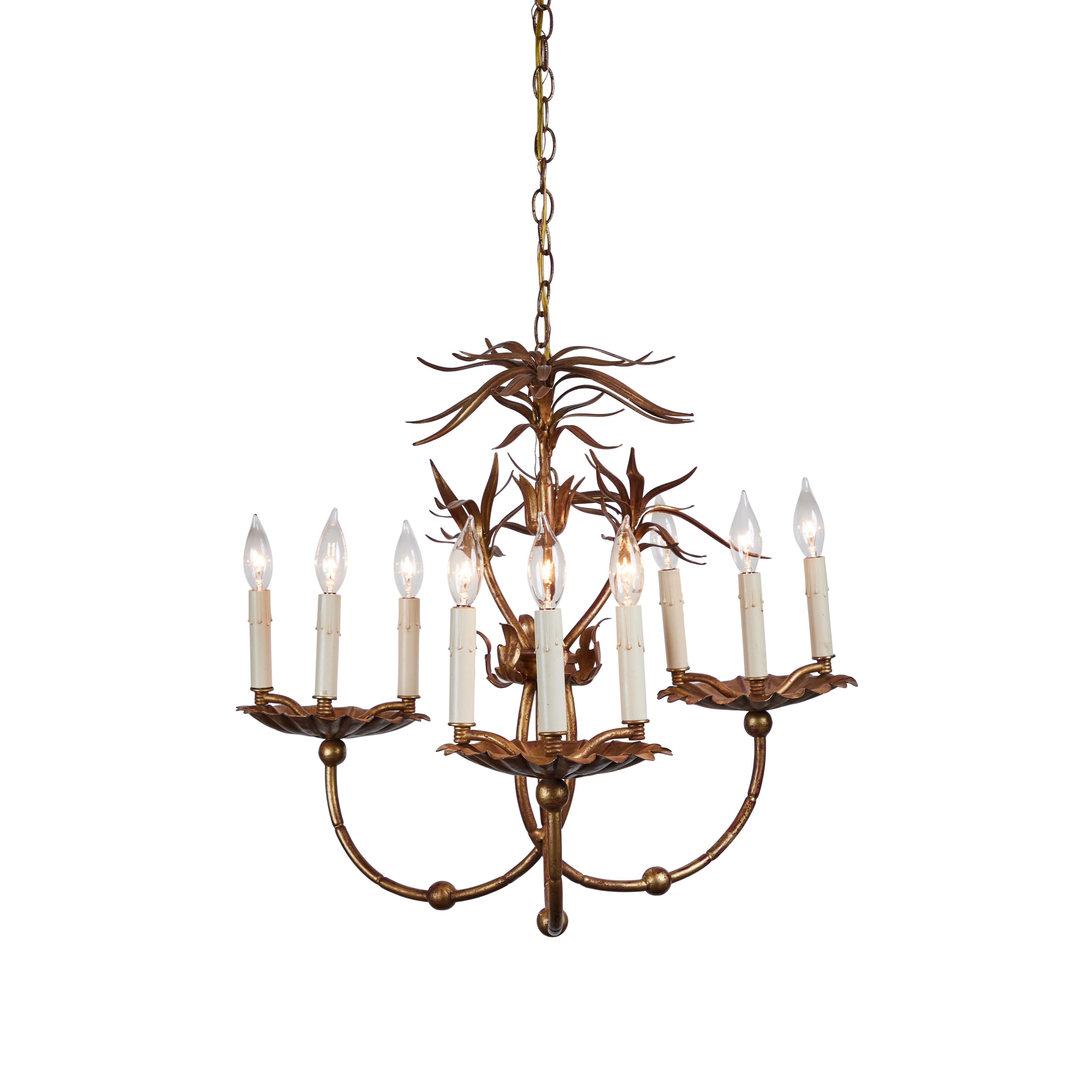 This graceful vintage Chinoiserie style 3-arm faux bamboo hanging chandelier has 9 lights and has been newly rewired. Newly refinished in a distressed gold wash with red showing through, this finish highlight the faux bamboo arms and the flora