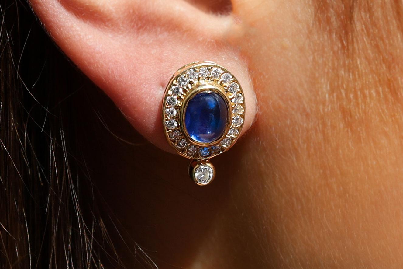 Velvety navy blue cabochon sapphires command your attention in these vintage 1970s estate earrings. Together weighing 3 carats with a rich, glossy tone and surrounded with sparkling, crisp colorless diamonds in an oval symphony of 18kt gold. Topped