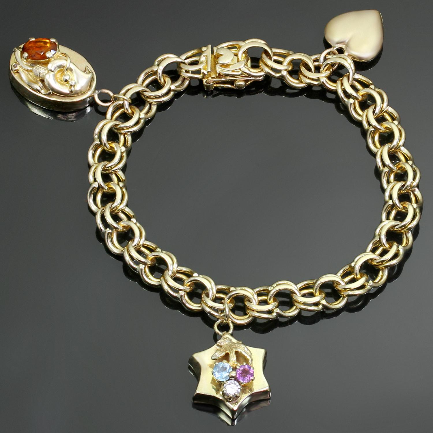 Ce bracelet classique à maillons vintage est fabriqué en or jaune 14 carats et comporte 3 charmes - un charme en forme de cœur (avec quelques bosses et rayures), un charme en forme d'étoile serti de 3 pierres précieuses à facettes et un charme ovale