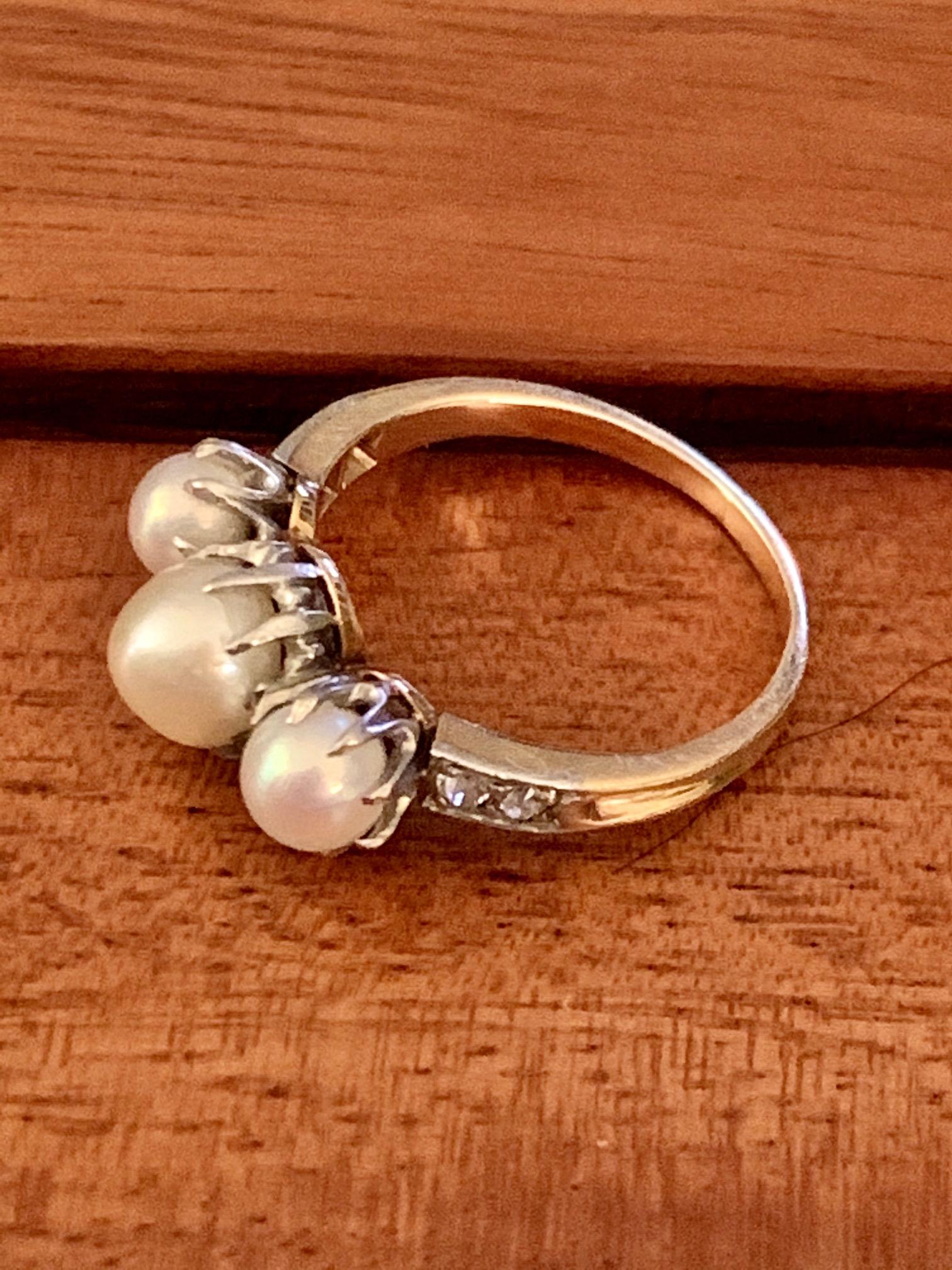 Dieser Vintage-Ring enthält drei Perlen; 2 sind 5 mm groß und 1 ist 6 mm groß.  Die Perlen werden von vier 2,1 mm großen Diamanten im Euro-Schliff mit einem Gewicht von 0,20ctw akzentuiert.

Größe: 6 - Dieser Ring kann in der Größe angepasst werden,