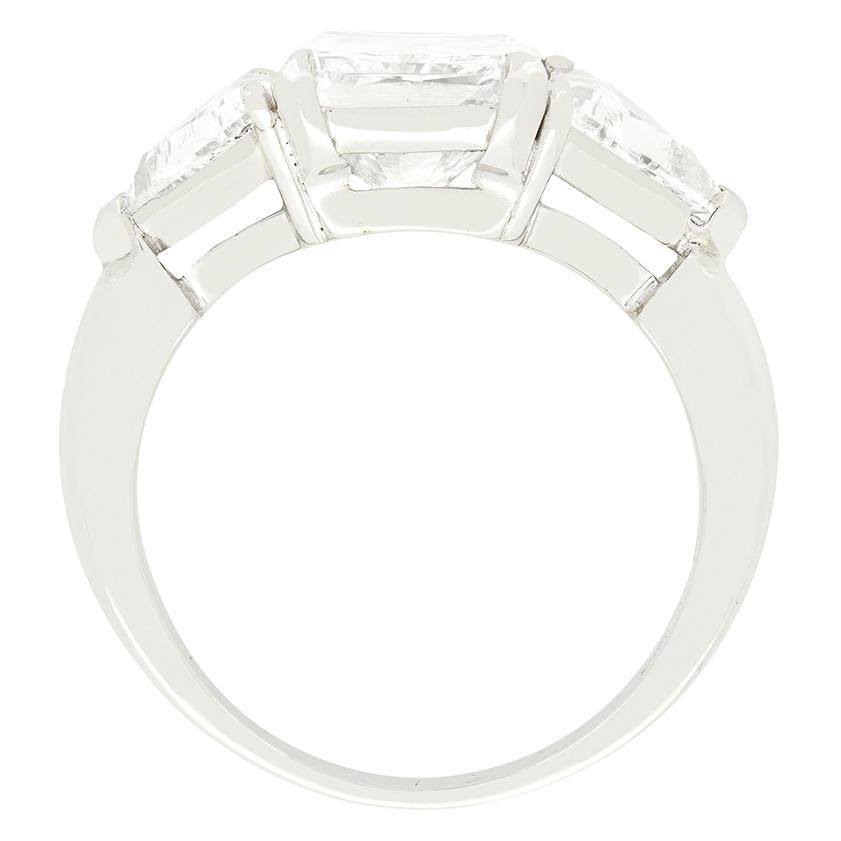 Con uno squisito diamante a taglio radiante da 3,01 carati al centro, questo anello vintage a tre pietre che lascia a bocca aperta è stato realizzato negli anni Settanta. Il diamante centrale è stato certificato dalla GIA con colore D e purezza SI2.